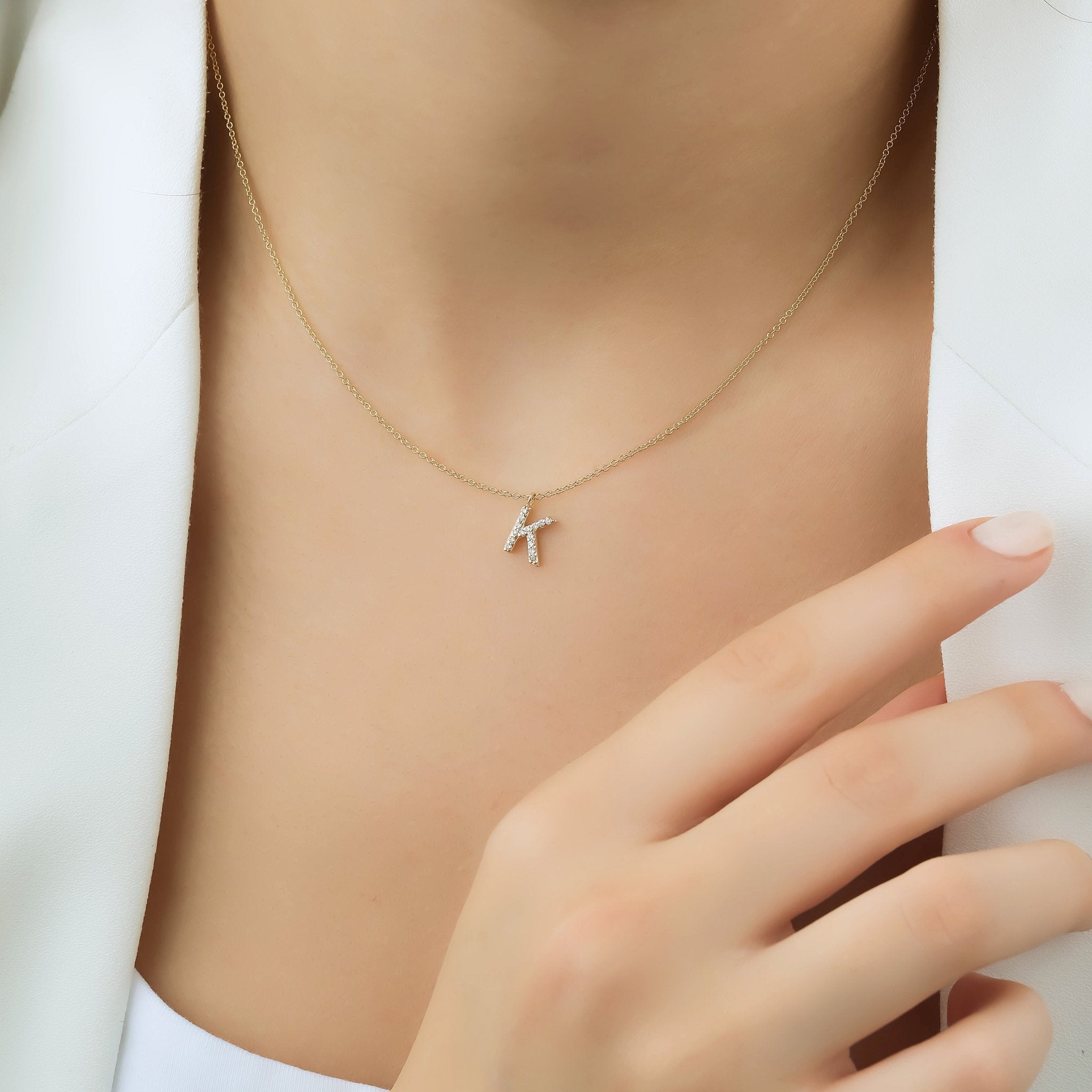 14K white gold diamond initial necklace featuring letter K, displayed on a model's neck.