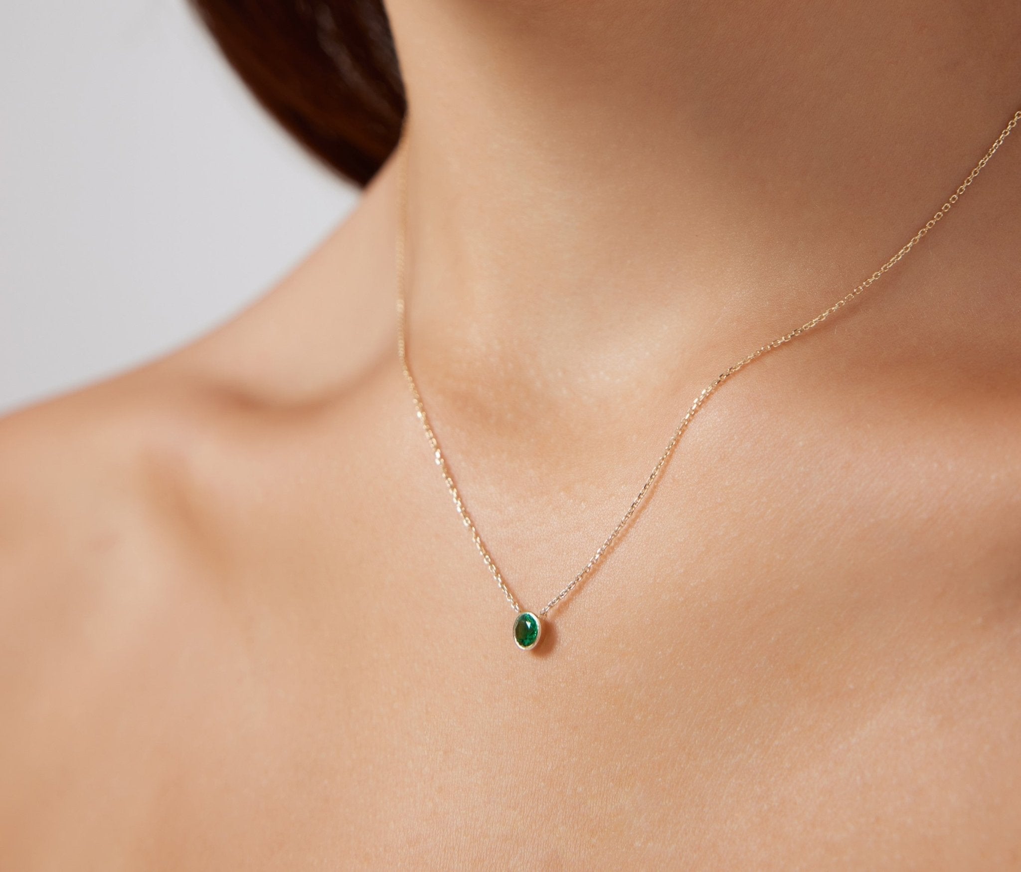 Model wearing a 14K solid white gold bezel set solitaire emerald necklace, showcasing its elegant and minimalist design.