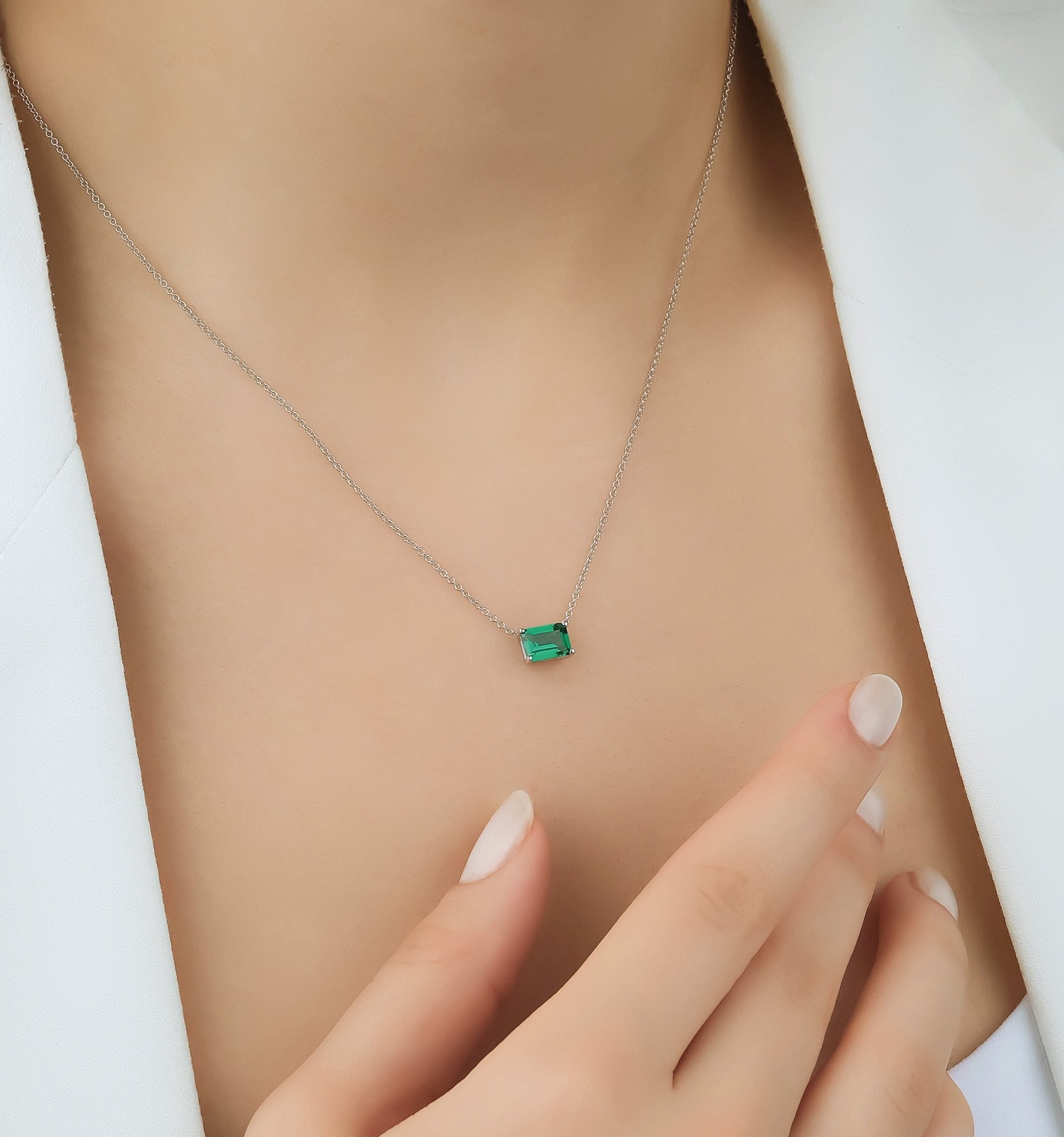 14K white gold emerald cut solitaire emerald necklace on a model, showcasing its dainty design and elegance.