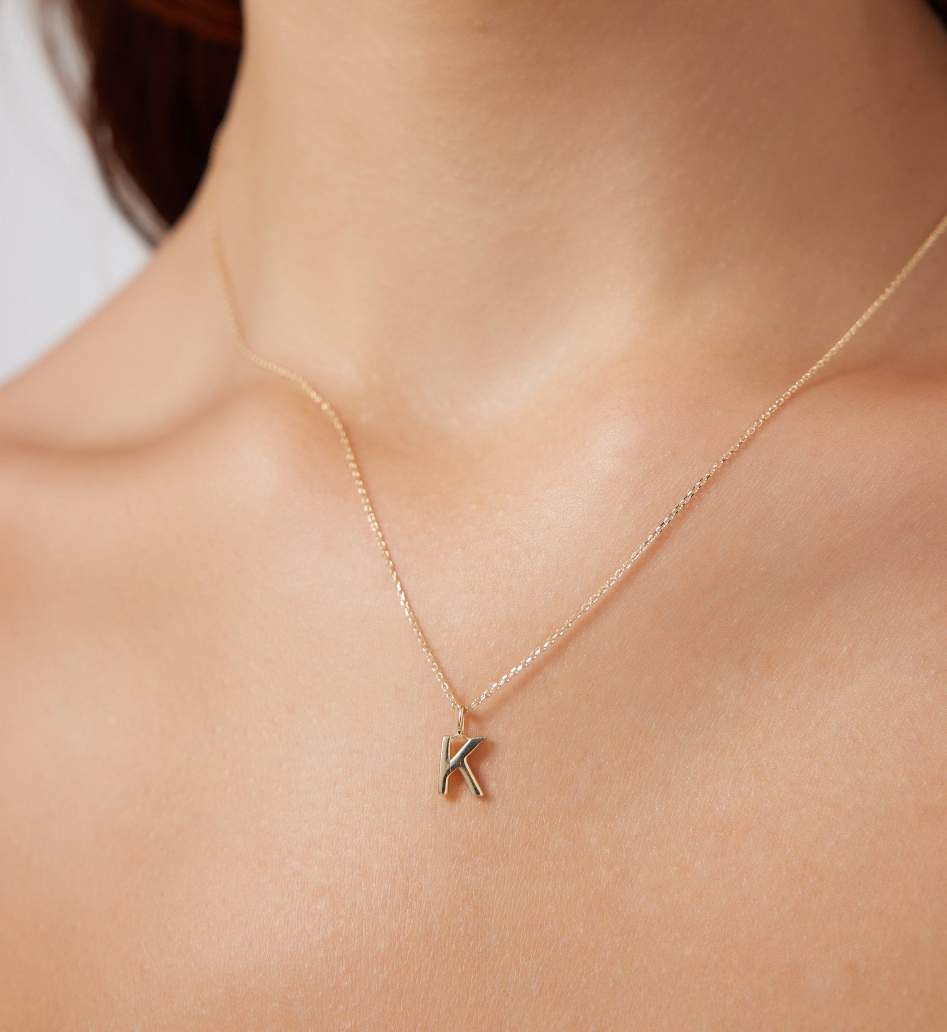 Dainty 14K solid white gold initial necklace featuring the letter K, worn on a delicate chain.