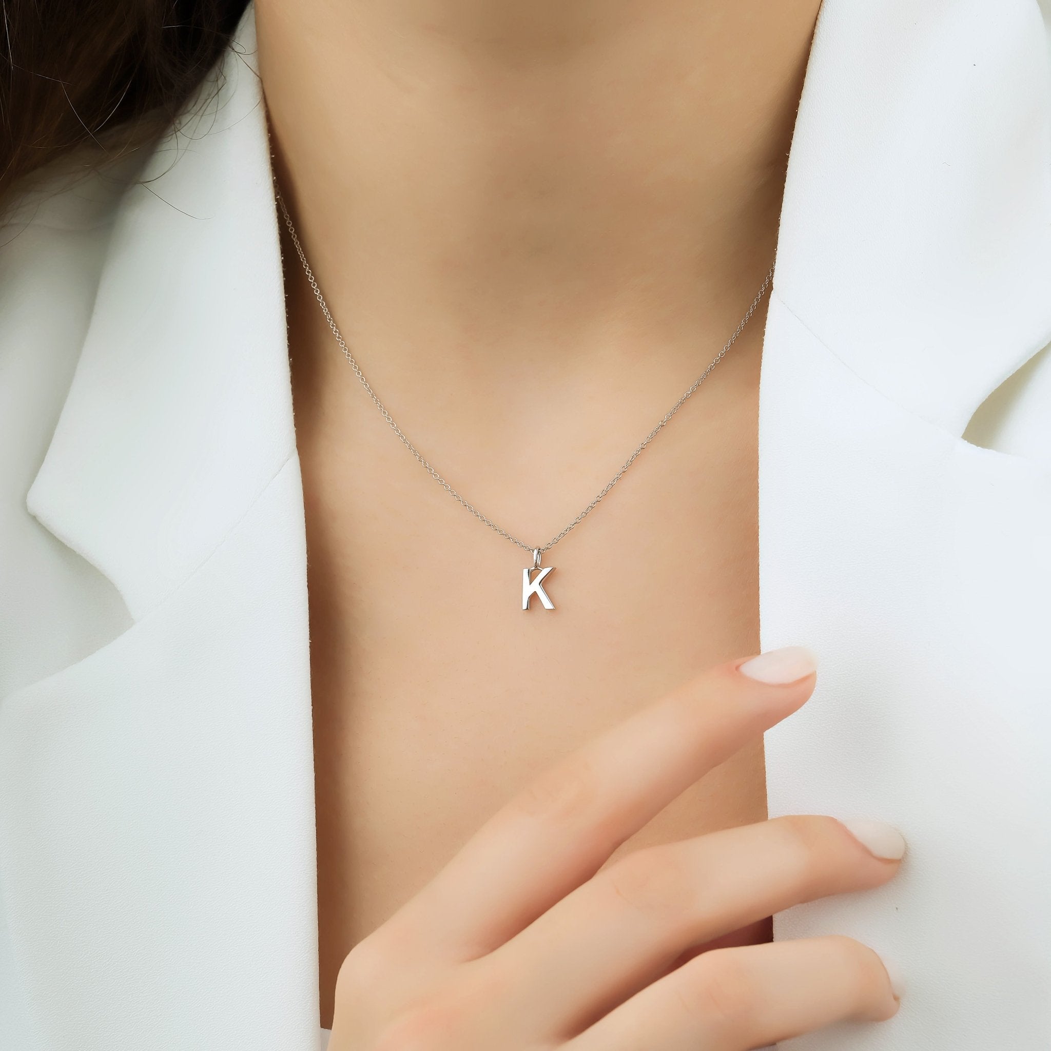 14K solid white gold initial necklace featuring letter K, dainty design worn on model's neck, elegant jewelry accessory.