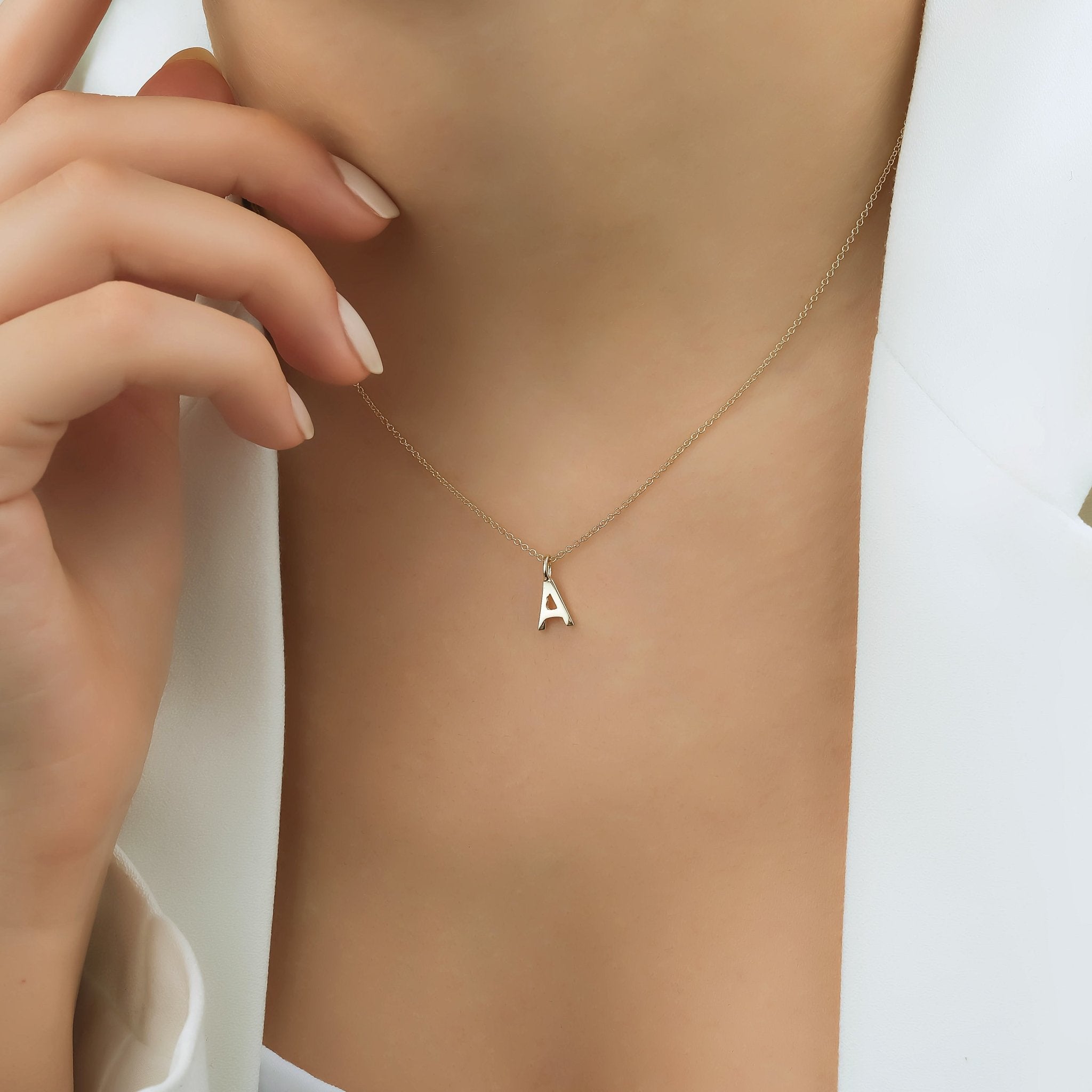 14K solid white gold initial necklace featuring a dainty letter A, elegantly displayed on a model's neck.