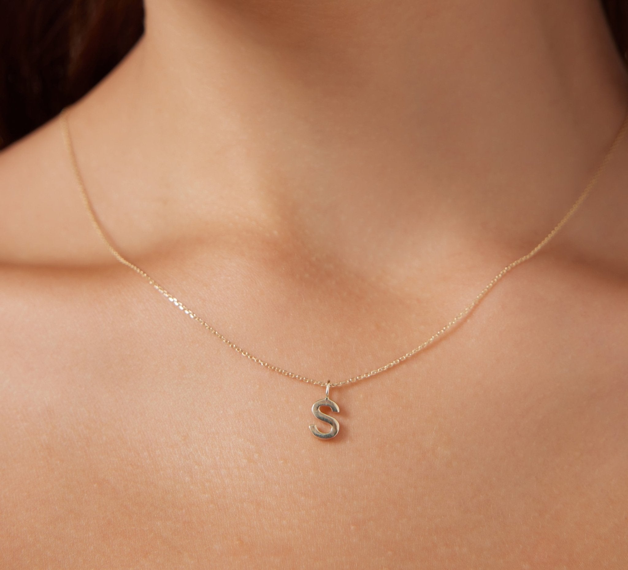 Dainty 14K solid white gold initial necklace featuring the letter S, displayed elegantly on a person's neck.