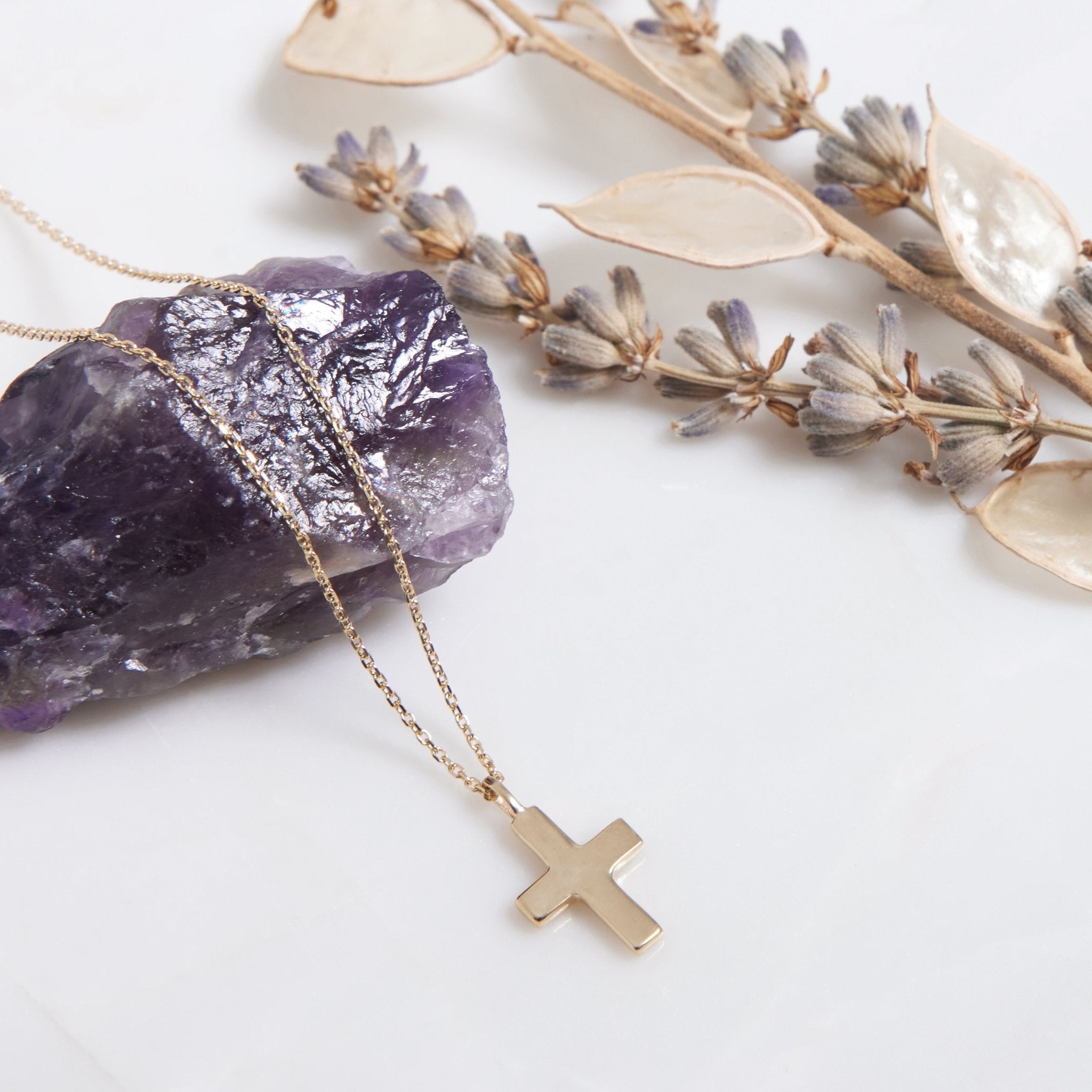 14K solid white gold minimalist cross necklace on a purple crystal background with dried flowers, showcasing elegant design.