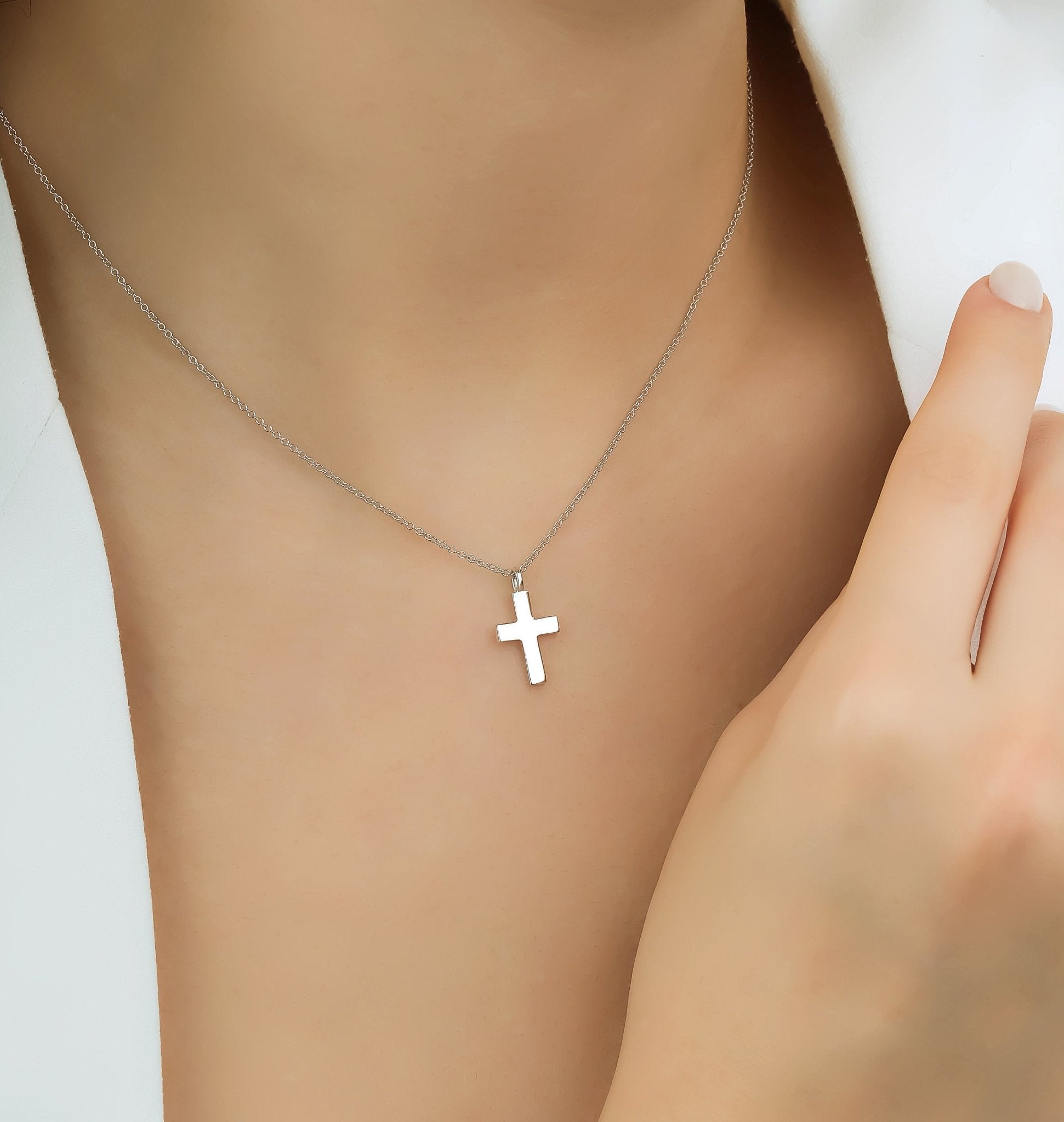 Minimalist 14K solid white gold cross necklace on a model's neck, showcasing elegance and simplicity.