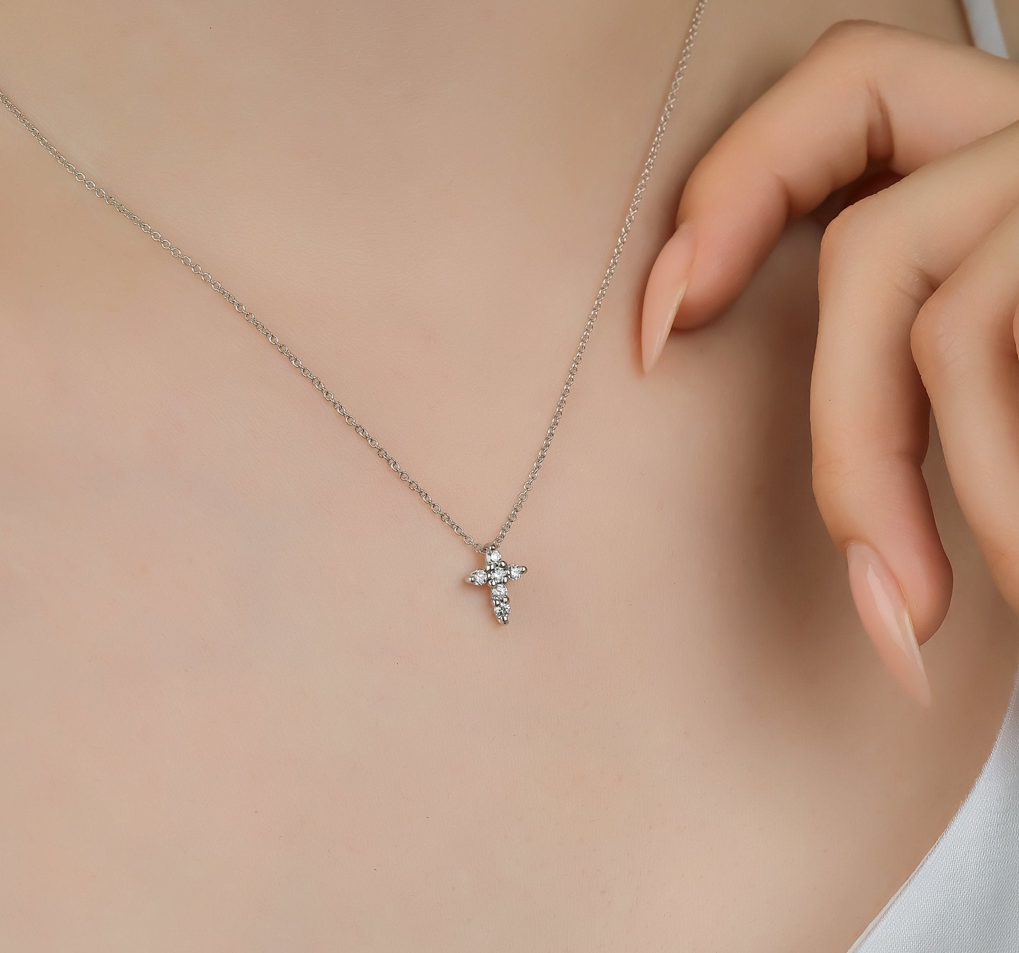Dainty 14K solid white gold minimalist diamond cross necklace worn on a model, showcasing its elegant design.