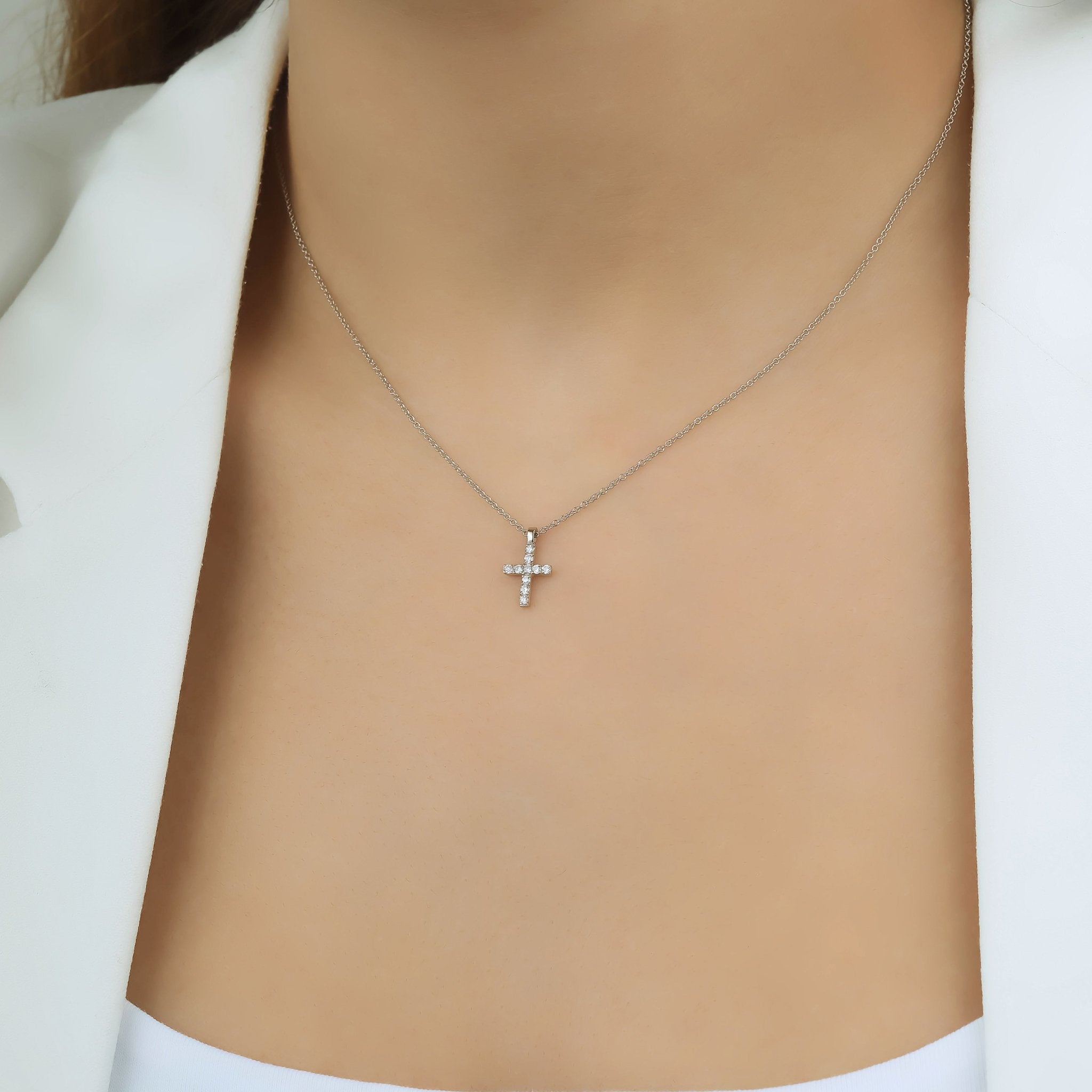 Dainty 14K solid white gold minimalist diamond cross necklace on a model.