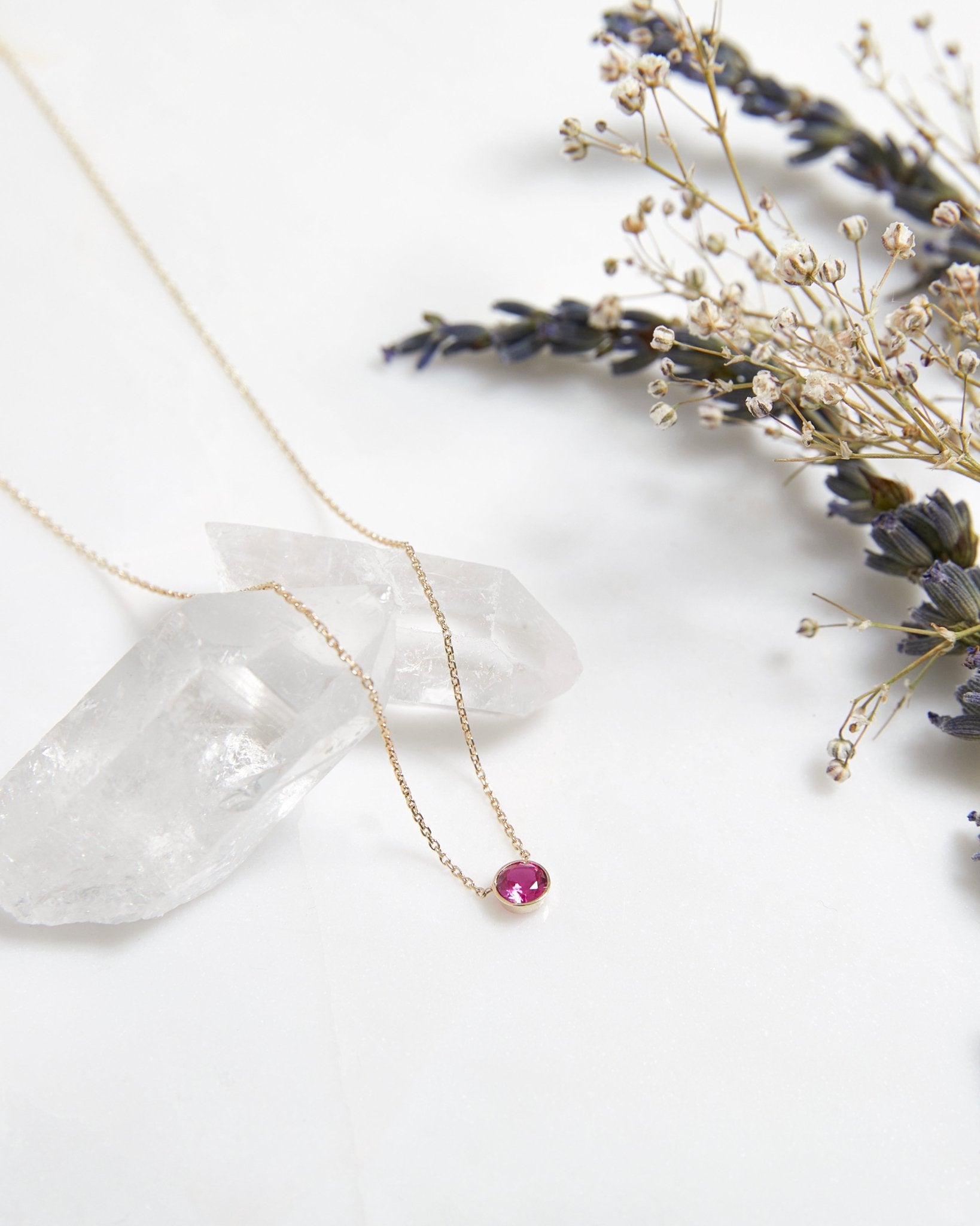 14K white gold 4mm bezel set solitaire ruby necklace with delicate chain, surrounded by lavender and clear crystals.