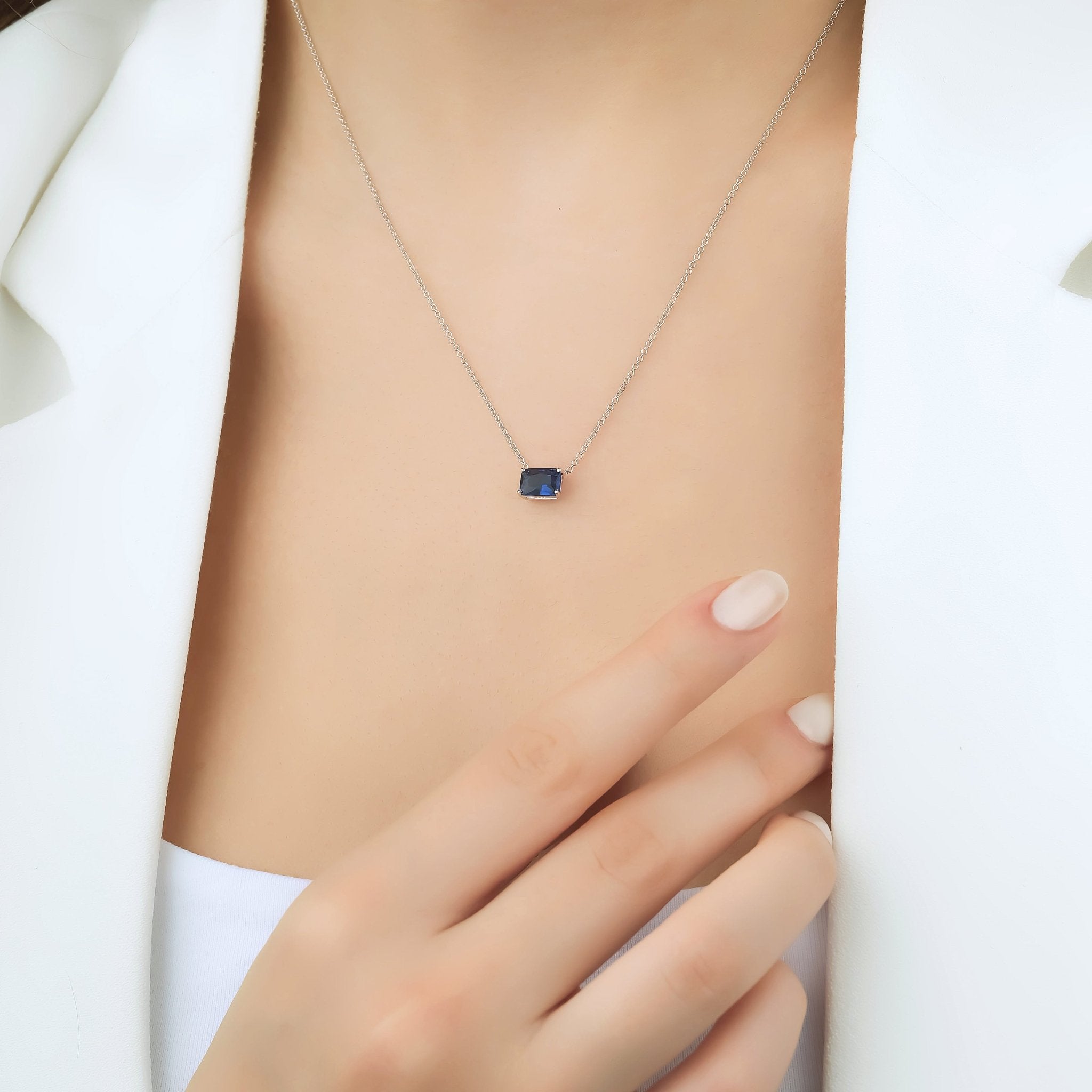 14K white gold emerald cut sapphire solitaire necklace worn on model, showcasing delicate design and minimalist elegance.