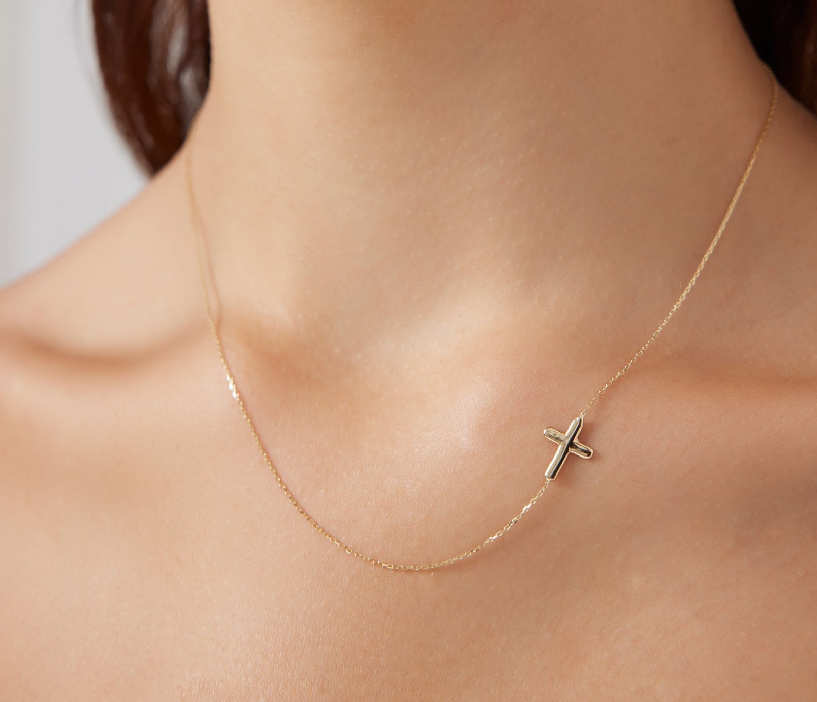 Minimalist 14K solid white gold sideways cross necklace worn on a woman's neck, showcasing its delicate design.