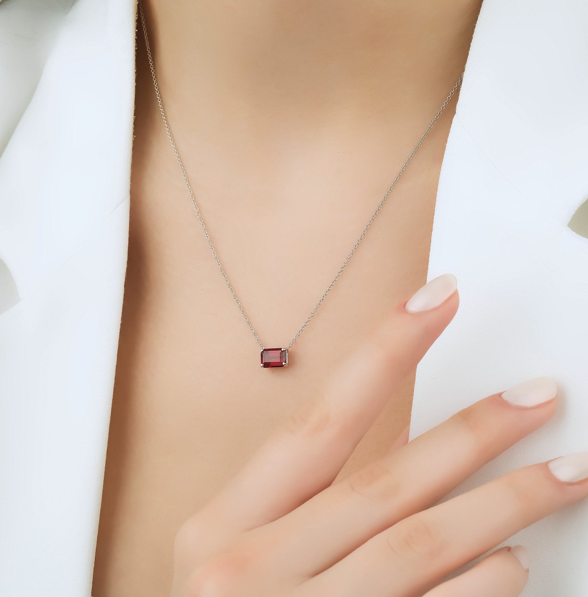 14K white gold emerald cut ruby solitaire necklace on model, highlighting dainty design and July birthstone.