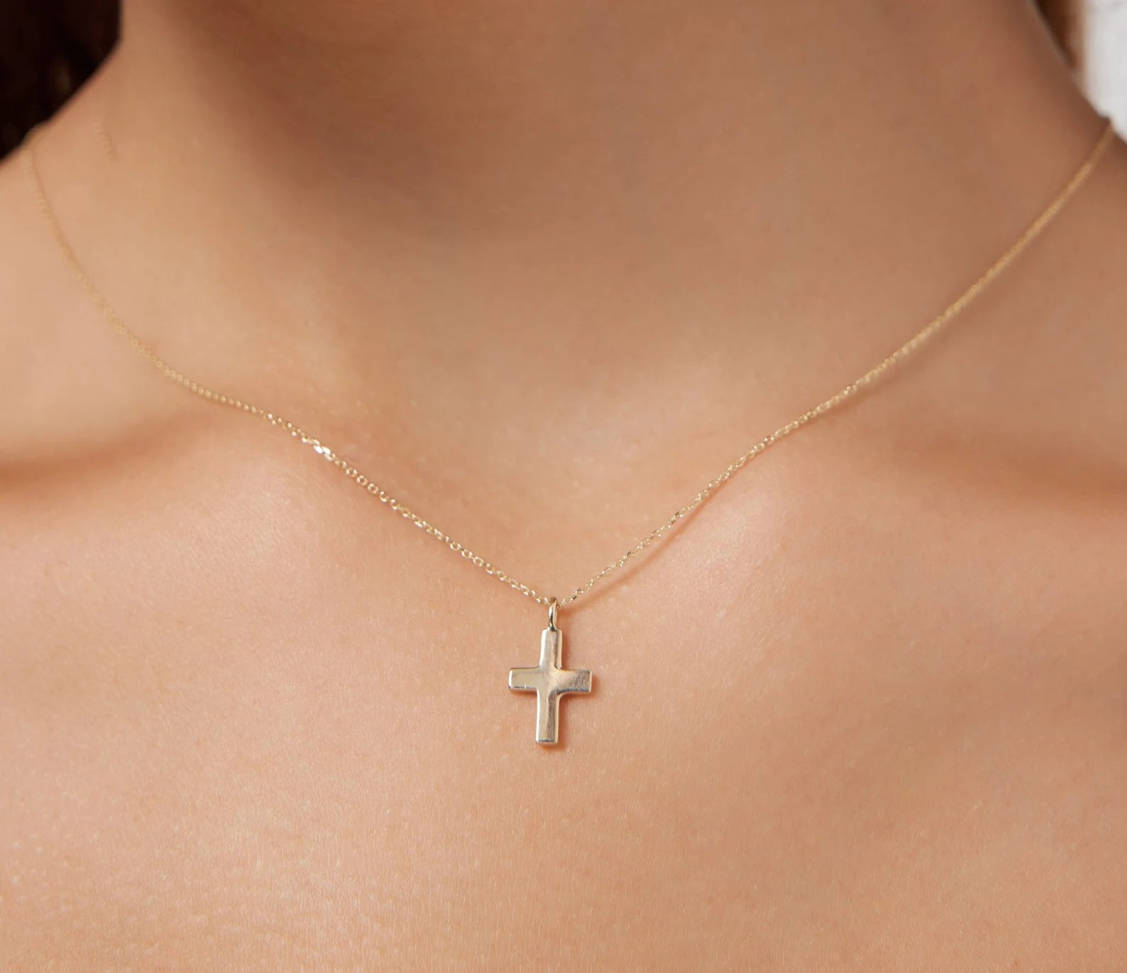 Minimalist 14K solid yellow gold dainty cross necklace on a model's neck, showcasing its elegant design.
