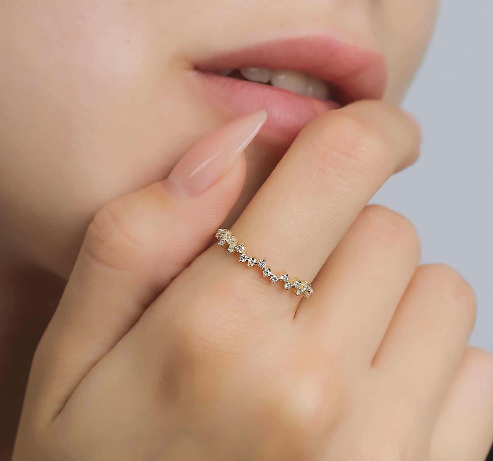 Dainty 14K yellow gold diamond cluster ring worn on hand with natural nails, showcasing minimalist design and shiny finish.