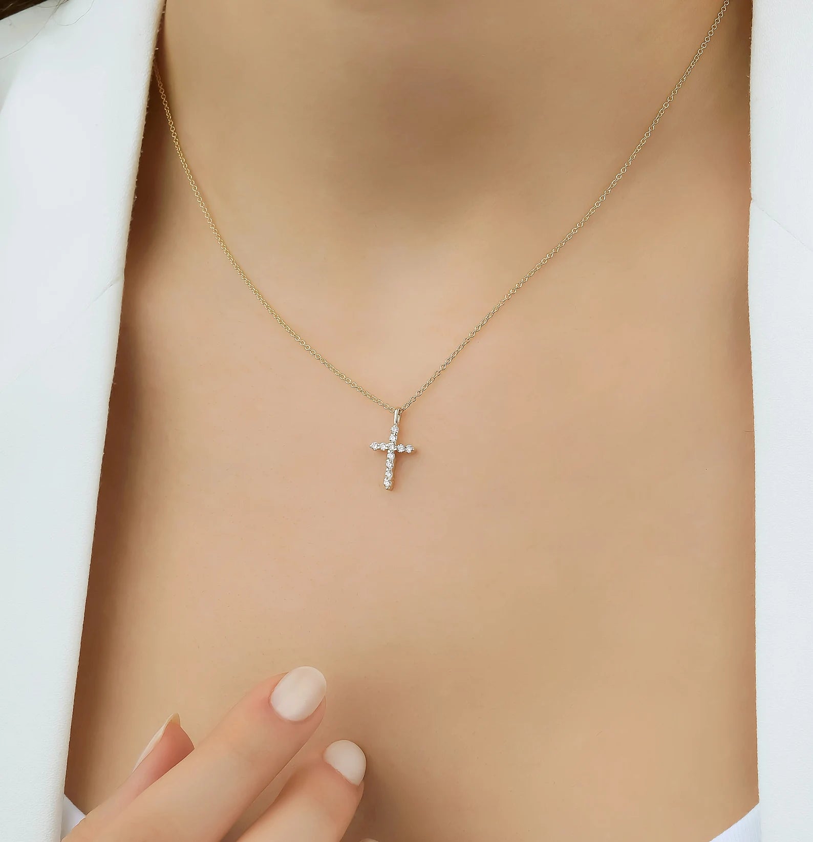 Dainty 14K solid yellow gold diamond cross necklace worn on the neck, featuring 11 sparkling diamonds.