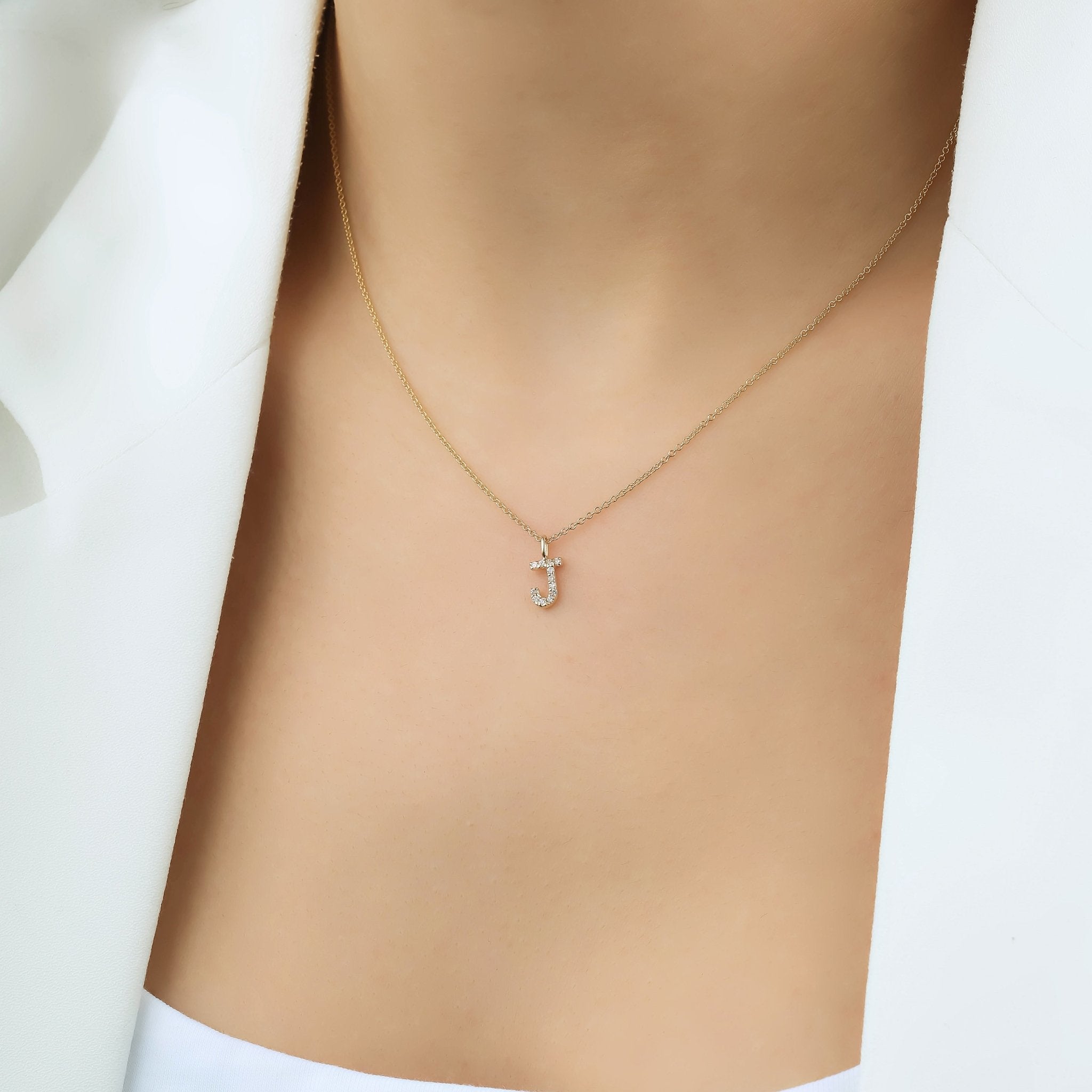 14K yellow gold diamond initial necklace featuring letter J, elegantly displayed on a model's neck.