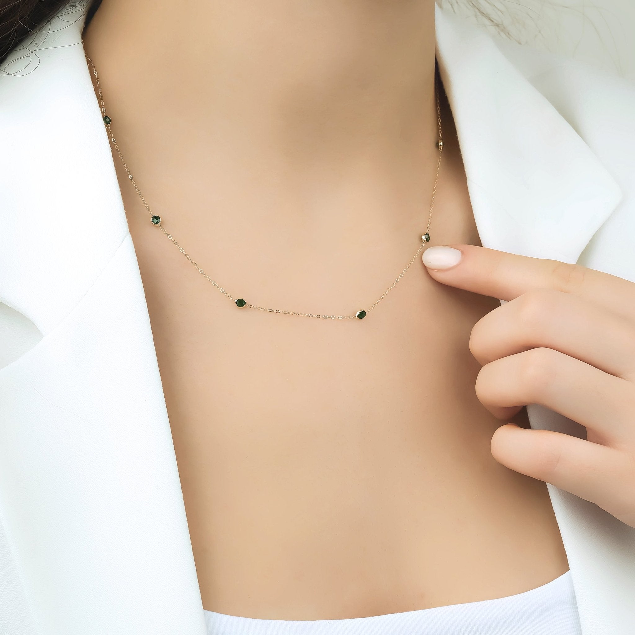 Model wearing a 14K solid yellow gold necklace with emerald stations, showcasing its elegance and design.