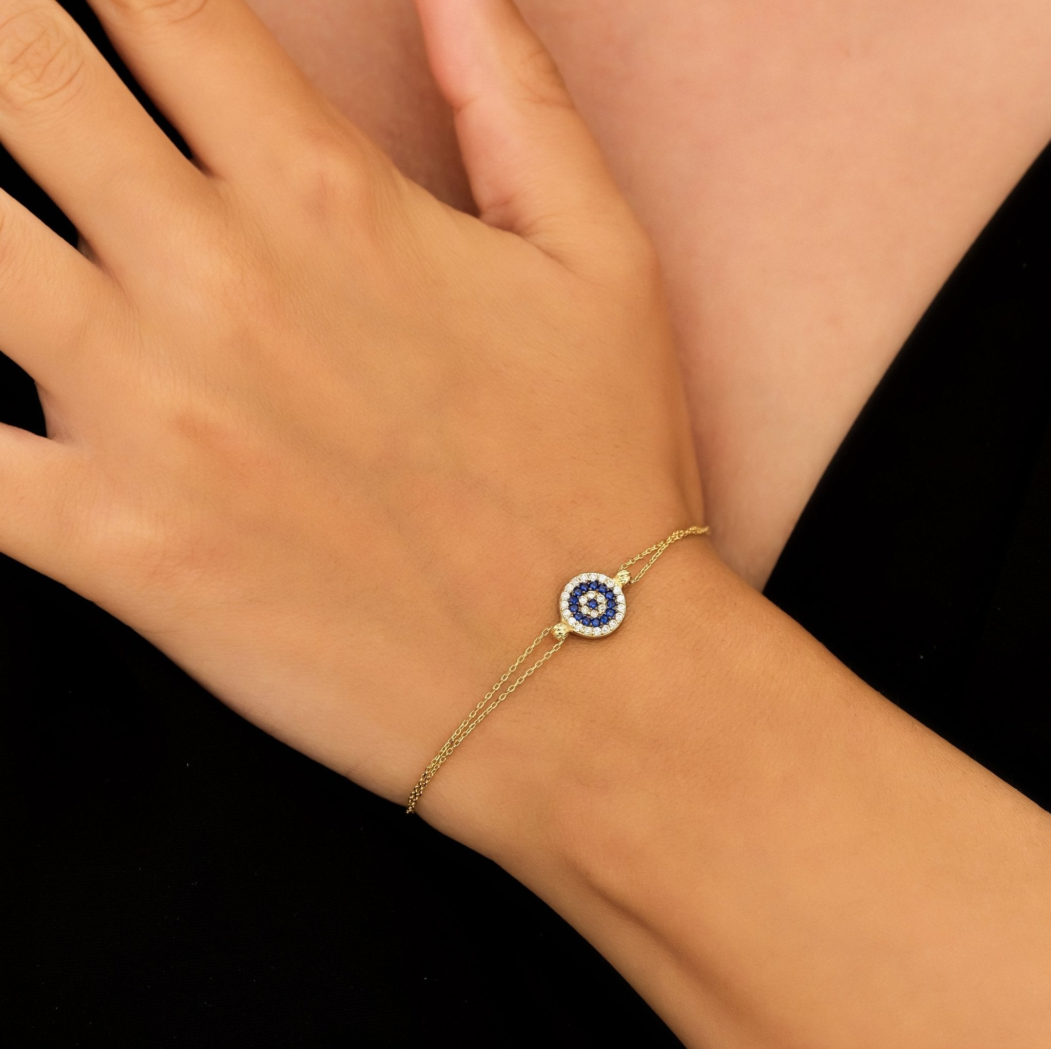 14K solid yellow gold evil eye bracelet worn on a hand, featuring colorful cz stones and a delicate chain design.