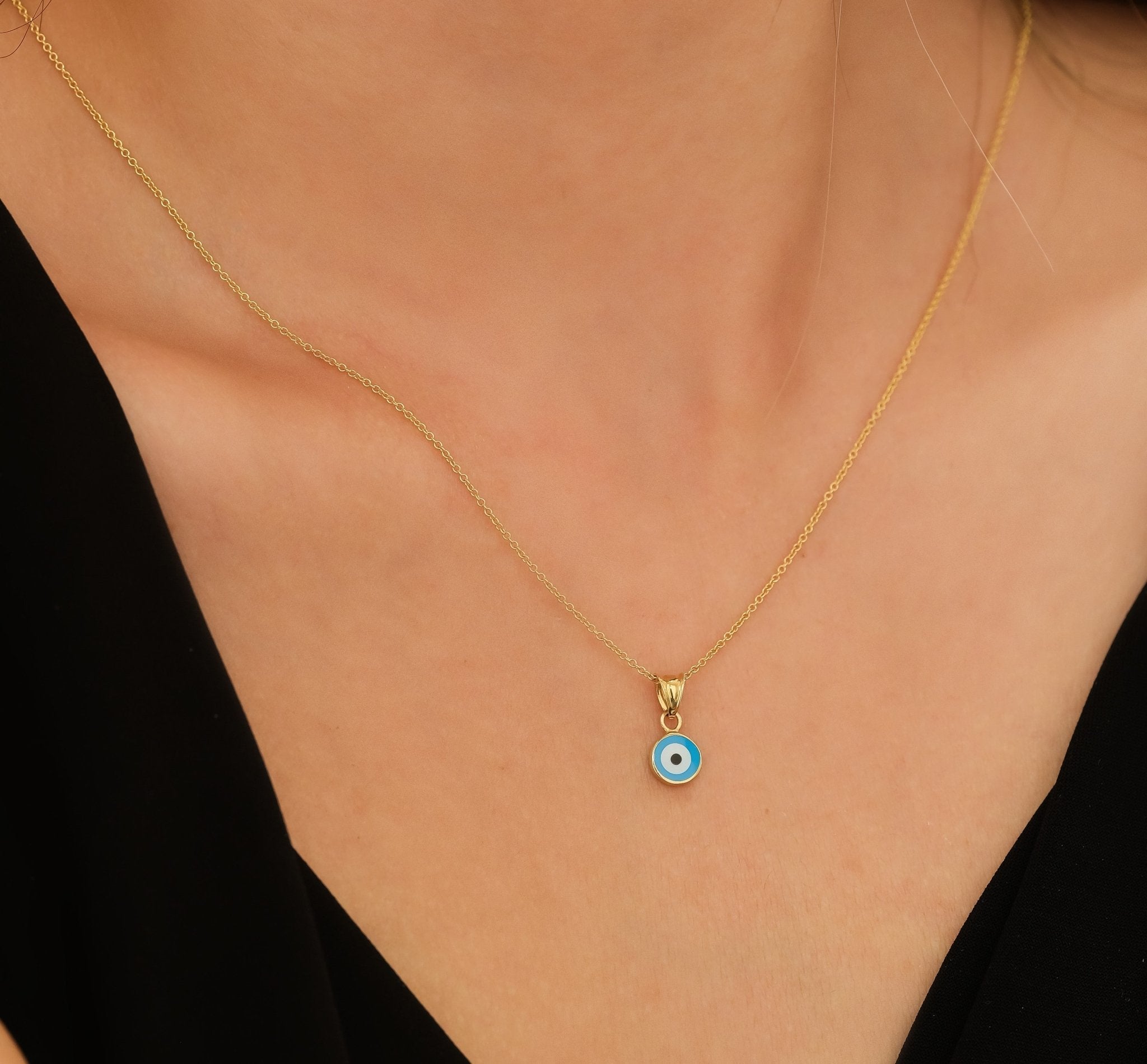 14K solid yellow gold evil eye necklace worn by a model, featuring a delicate round pendant with blue eye detail.