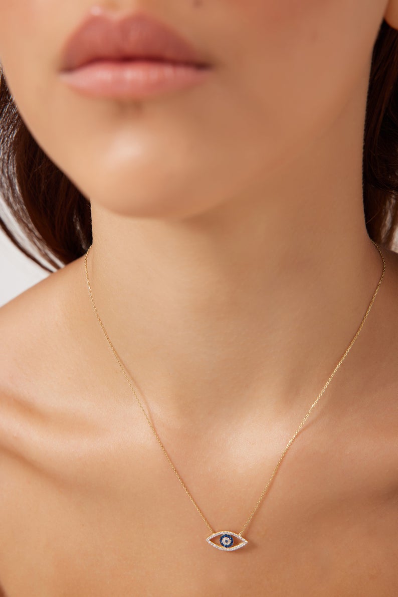 Close-up of a woman wearing a 14K solid yellow gold evil eye necklace with CZ. Minimalist design for everyday elegance.