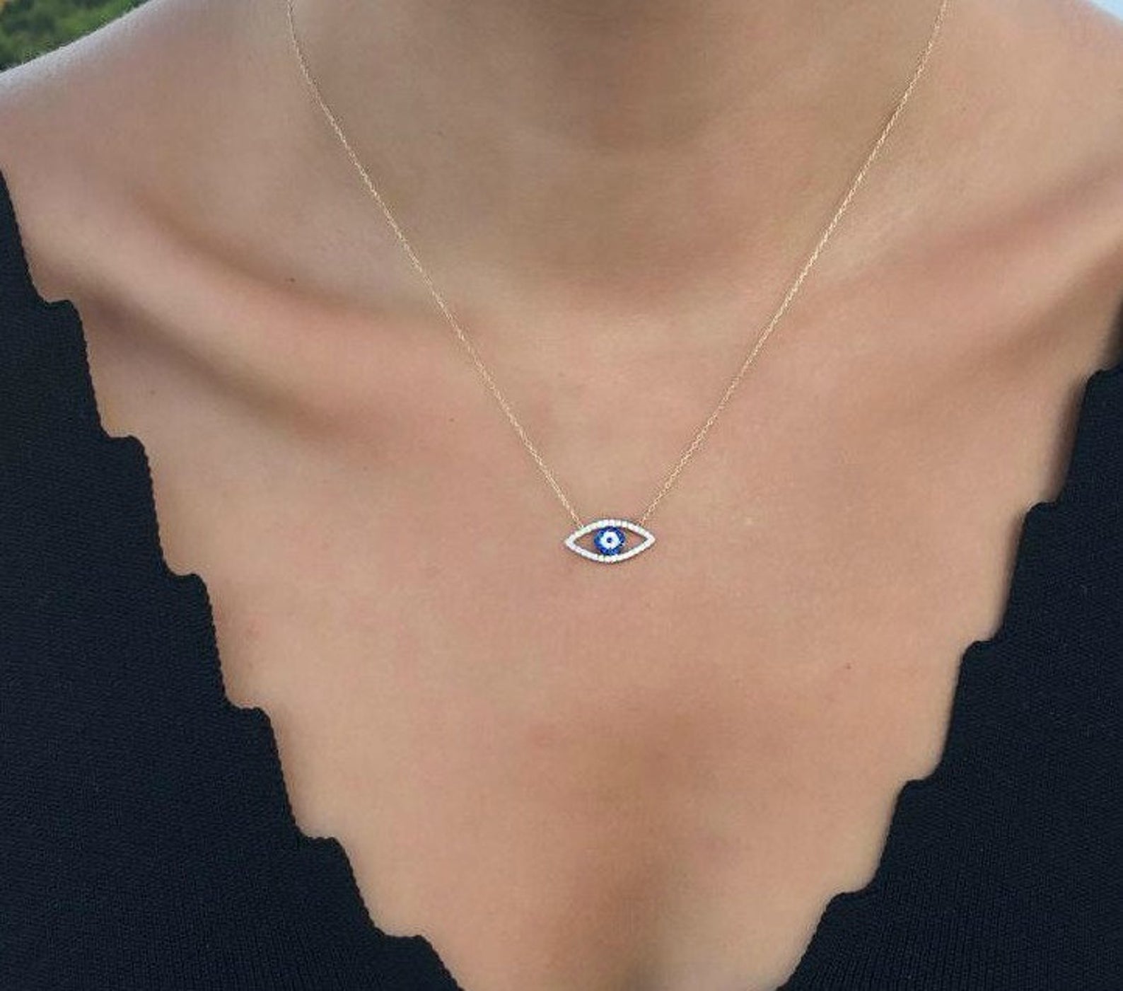 14K solid yellow gold minimalist evil eye necklace worn on a woman's neck, featuring a delicate eye shape design.