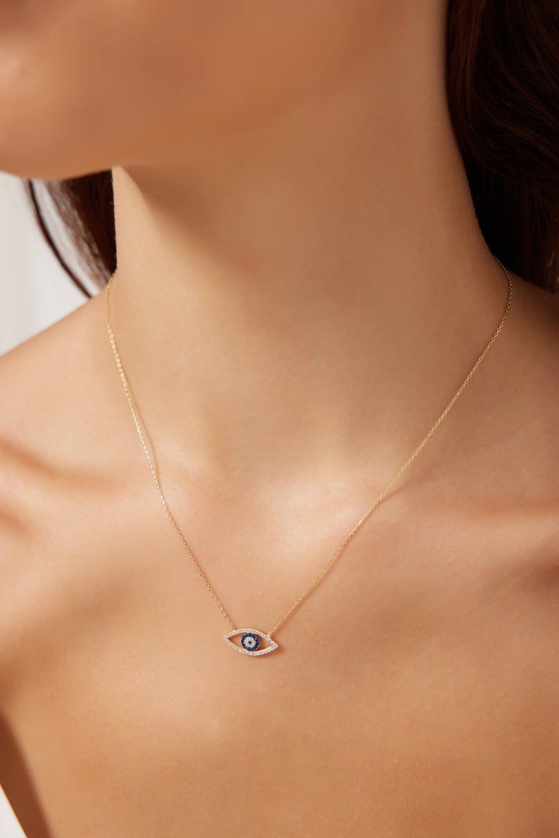14K solid yellow gold minimalist evil eye necklace worn on model, featuring dainty design with cubic zirconia.