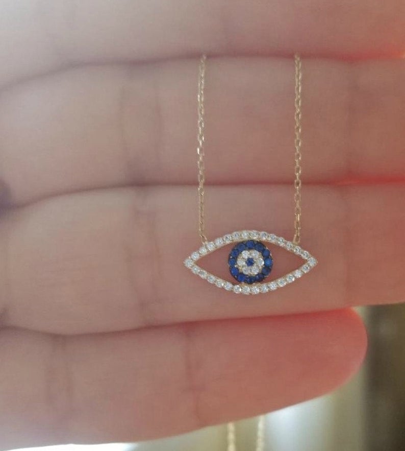 14K solid yellow gold evil eye necklace with CZ stones, held in hand, showcasing its minimalist design.
