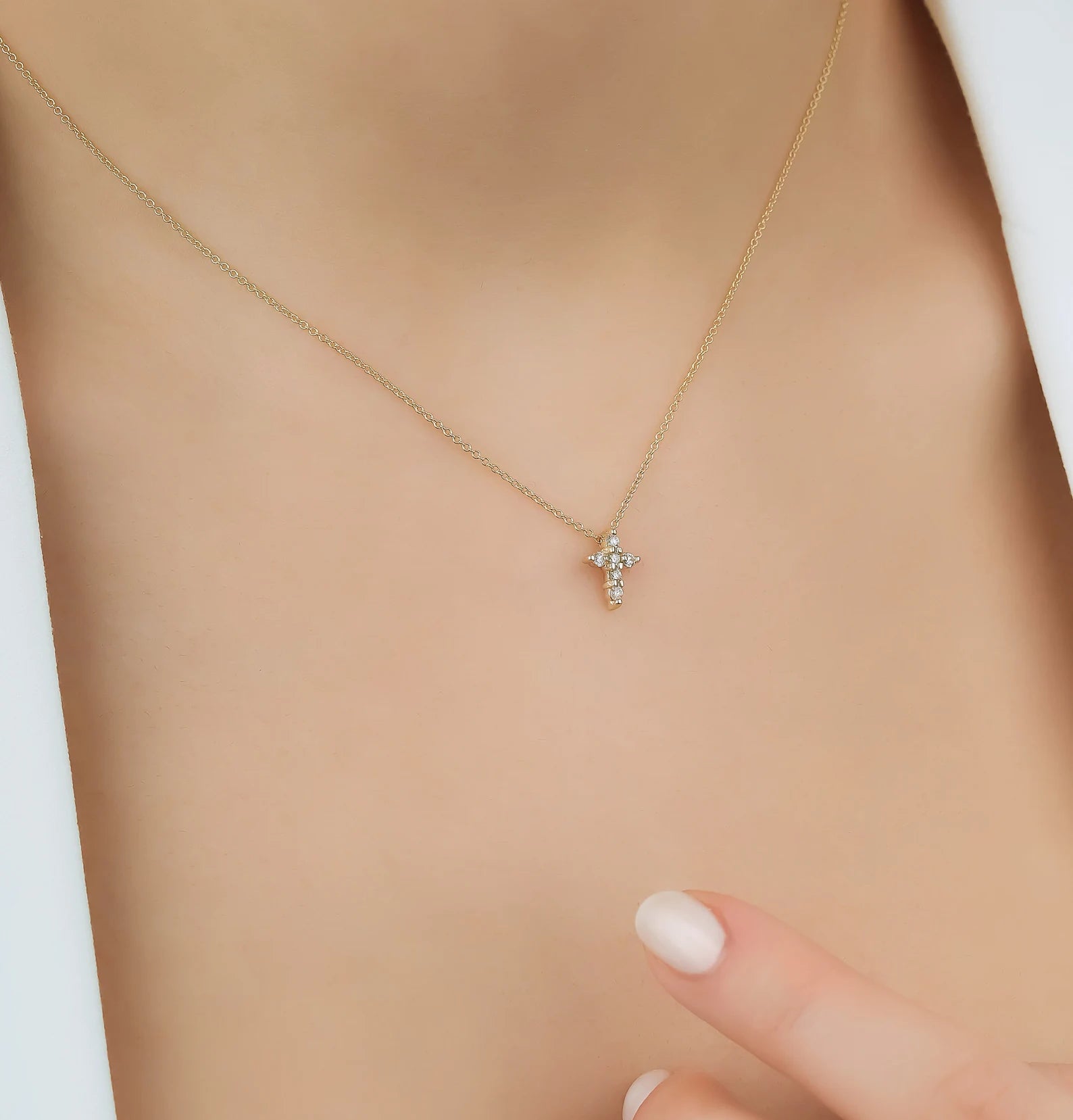 14K solid yellow gold minimalist diamond cross necklace worn; featuring delicate design with six sparkly diamonds.