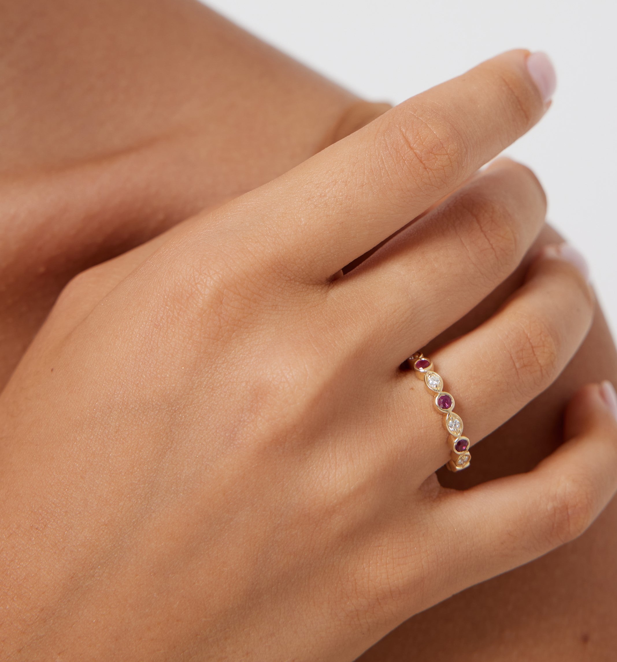 14K yellow gold wedding ring featuring rubies and diamonds worn on a hand, showcasing a shiny finish.