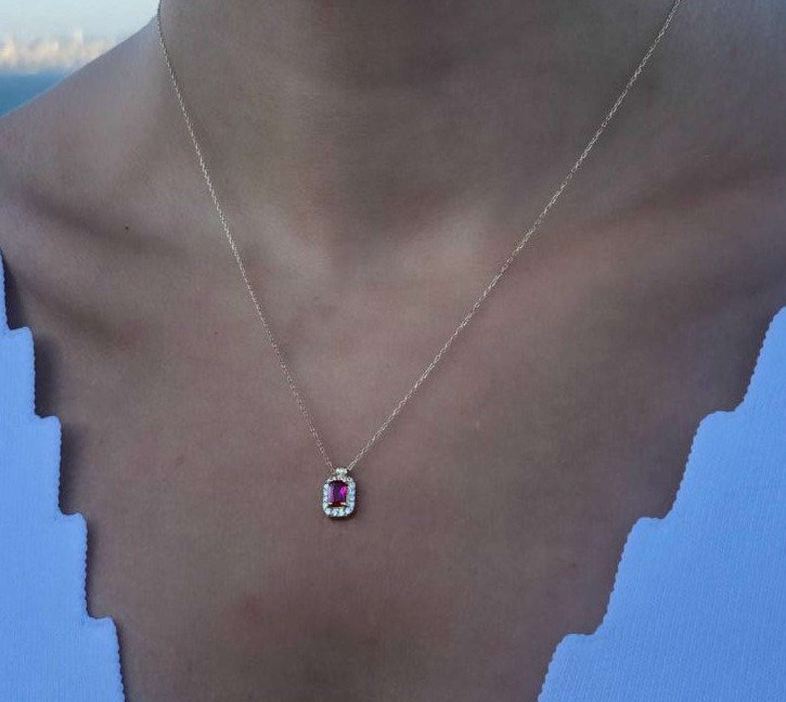 14K yellow gold emerald cut solitaire ruby necklace worn on a model, showcasing its dainty and elegant design.