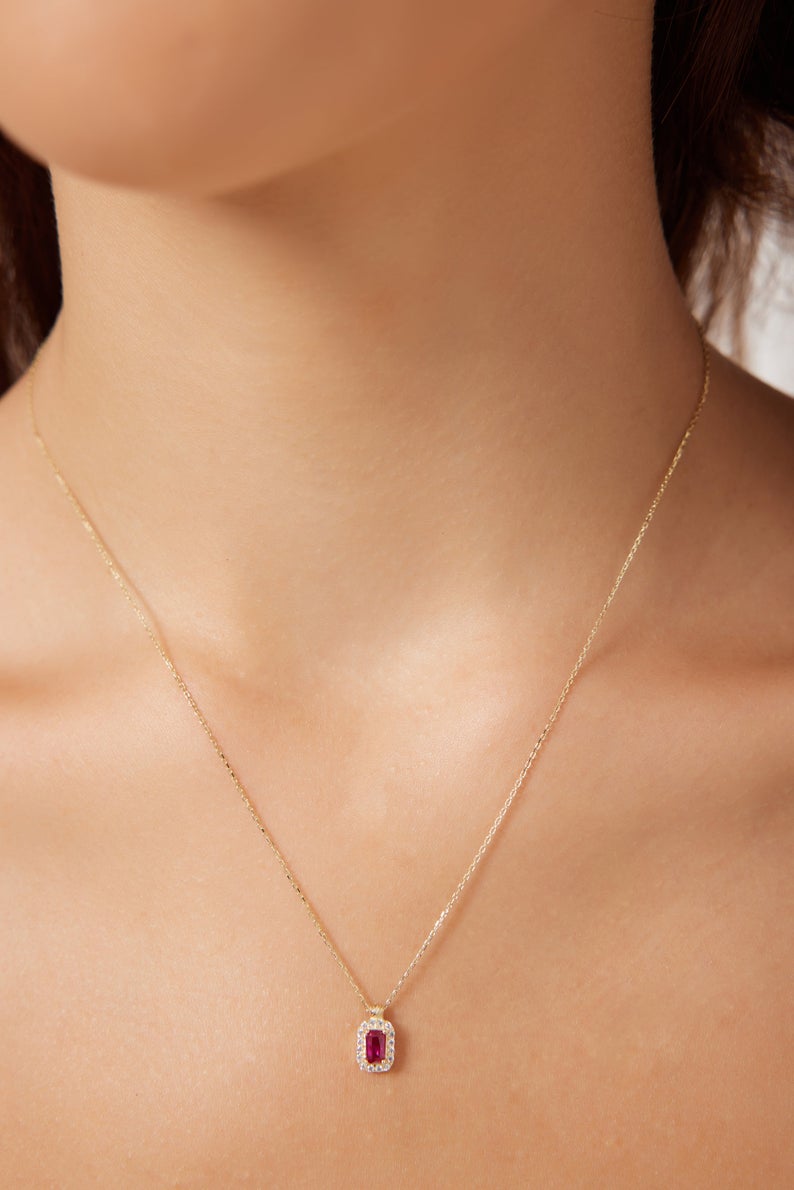 Close-up of a dainty 14K yellow gold necklace featuring an emerald cut ruby pendant, perfect for everyday wear.
