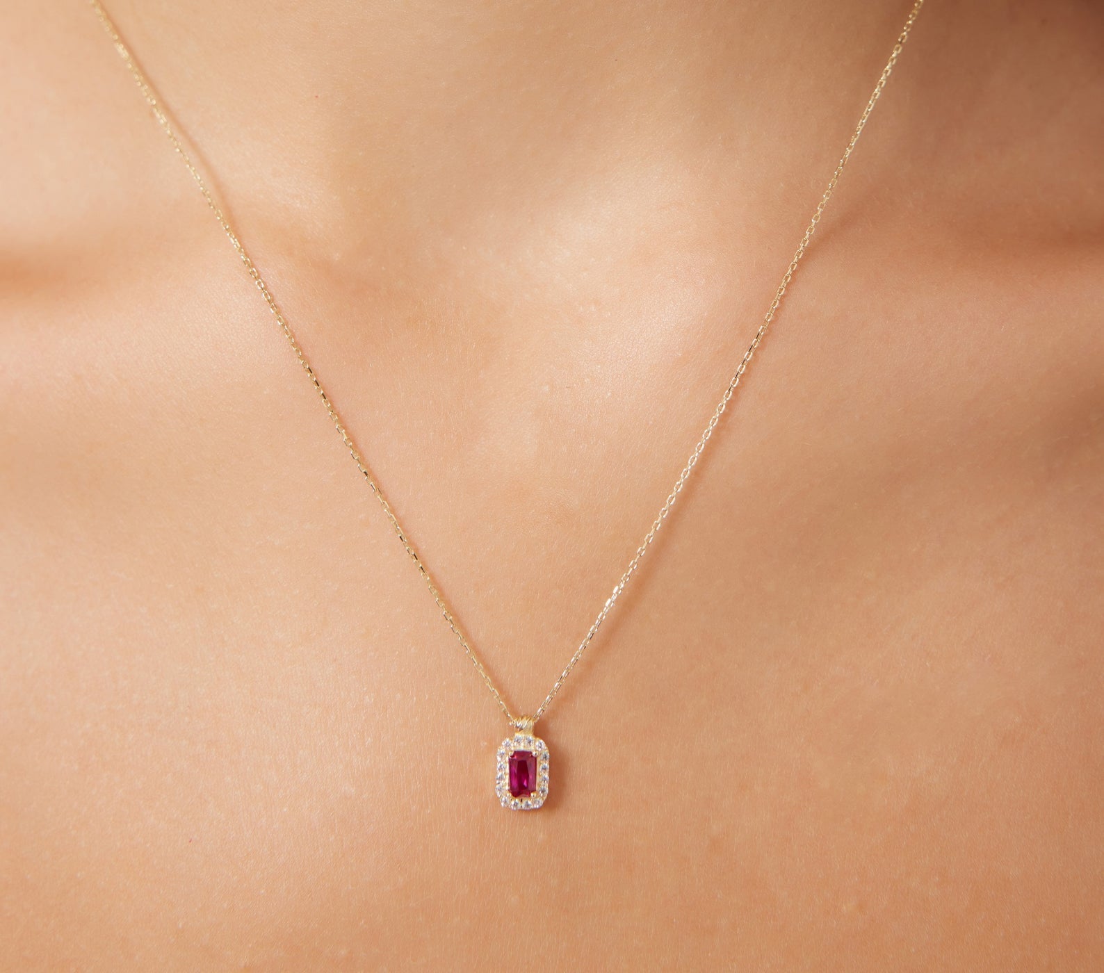 14K yellow gold emerald cut solitaire ruby necklace with CZ on a model, perfect for everyday elegance.