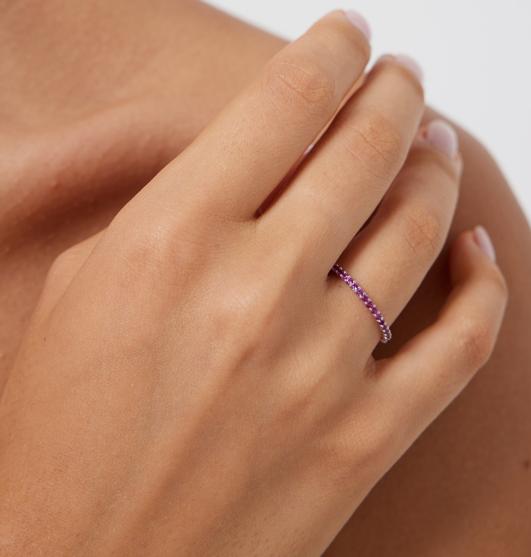 14K yellow gold full eternity ruby wedding band displayed on a hand, showcasing its elegant prong setting and vibrant stones.