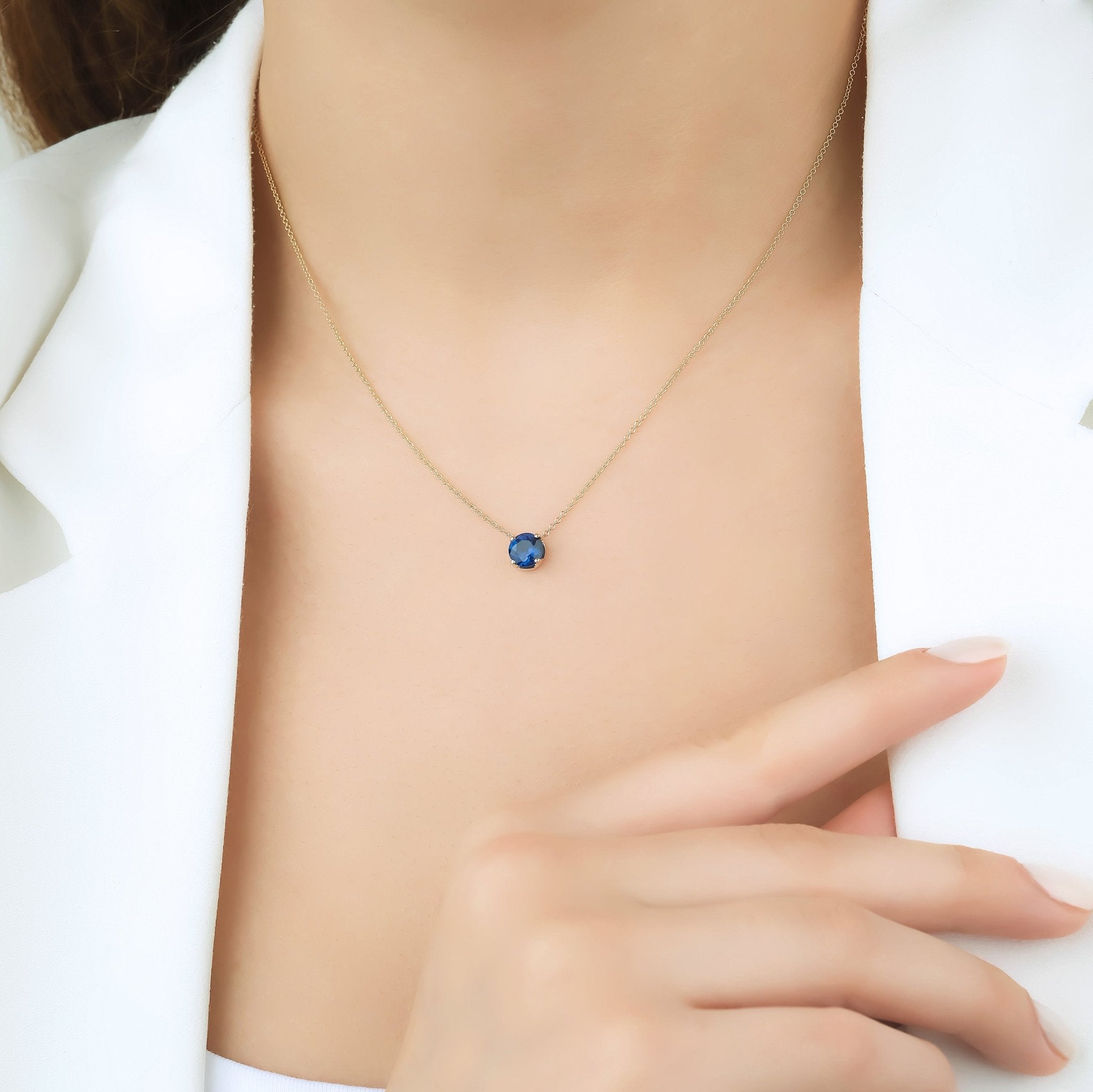 Elegant 14K solid yellow gold 6mm solitaire sapphire necklace on model, showcasing minimalist design.