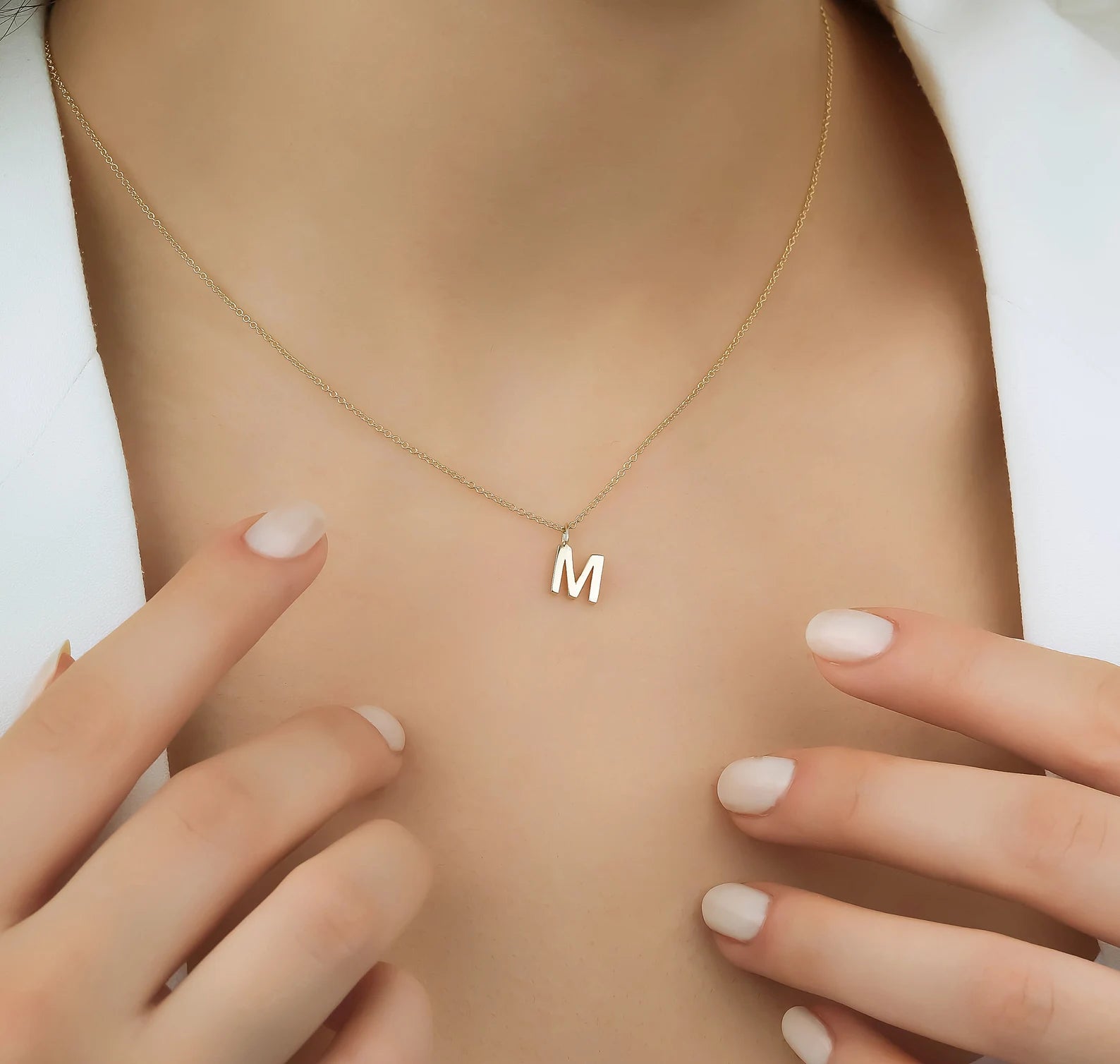 14K solid yellow gold initial necklace featuring the letter M, styled on a model.
