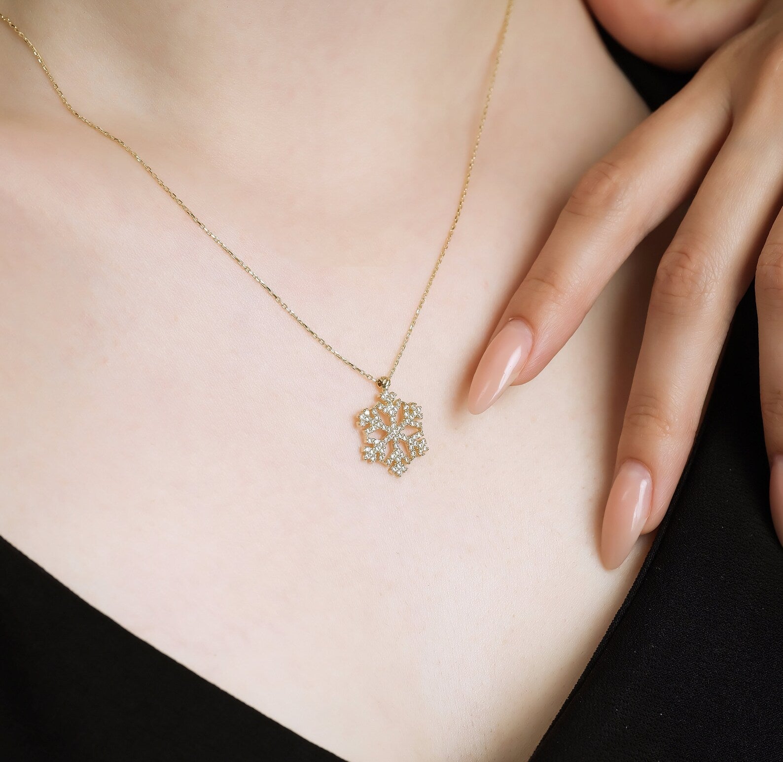Dainty 14K solid yellow gold snowflake necklace with CZ, worn on a model, perfect for everyday elegance.