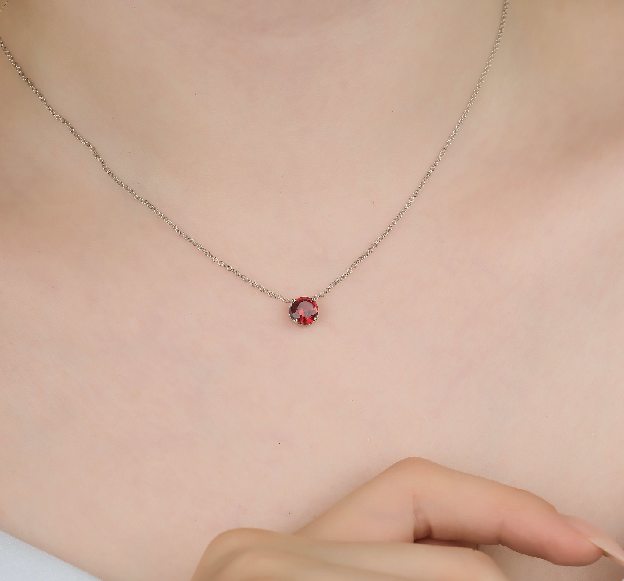 Dainty 14K yellow gold 6mm prong setting ruby solitaire necklace on a model's neck.