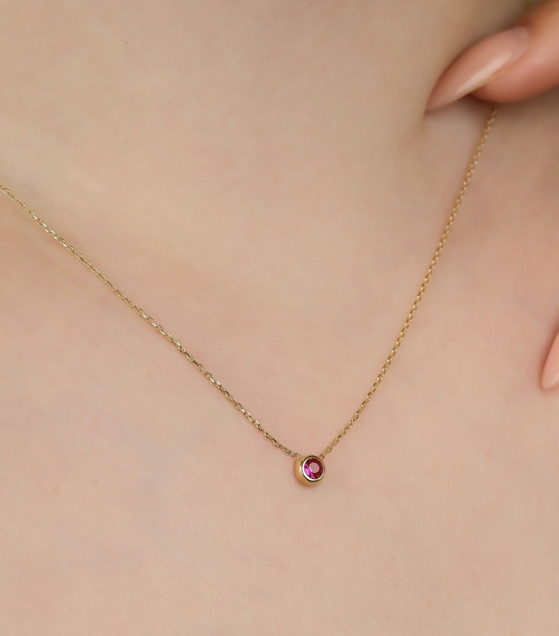 14K solid yellow gold solitaire ruby necklace worn on model, featuring a dainty 4mm ruby gem, perfect for everyday elegance.