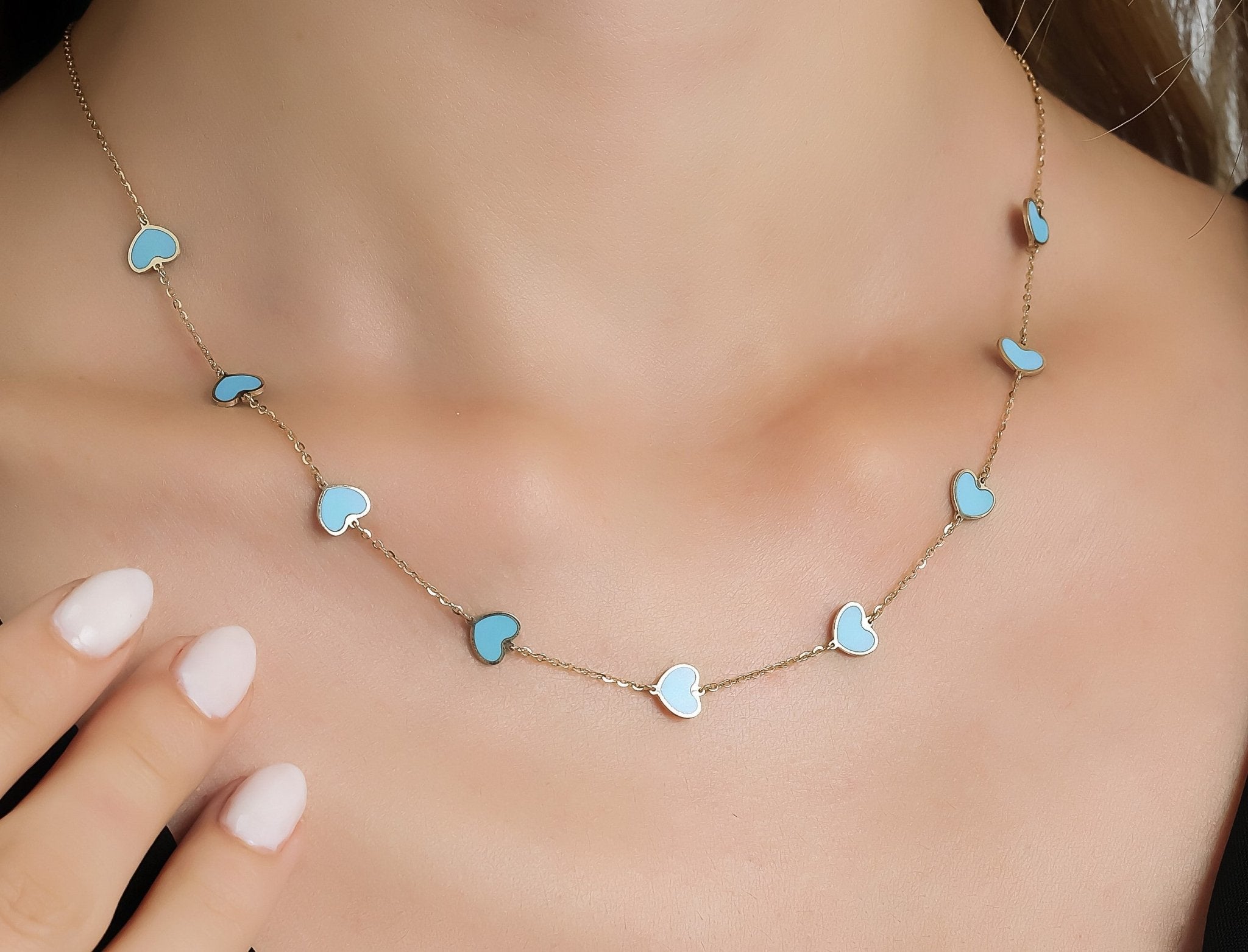 14K solid yellow gold turquoise heart necklace displayed on a woman's neck, featuring dainty heart charms.