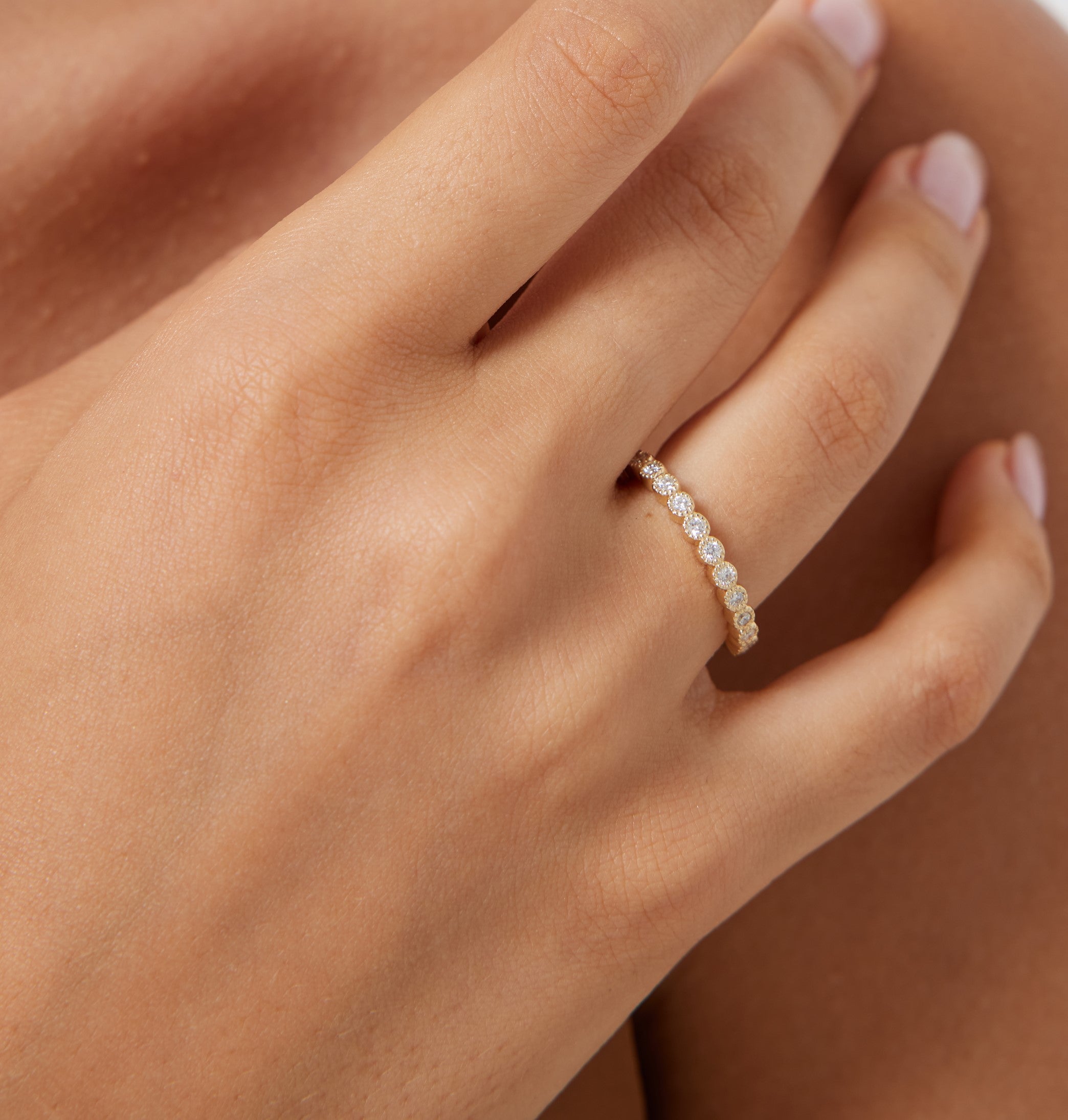 14K yellow gold half eternity diamond wedding ring on a person's hand, featuring 12 round diamonds with a shiny finish.