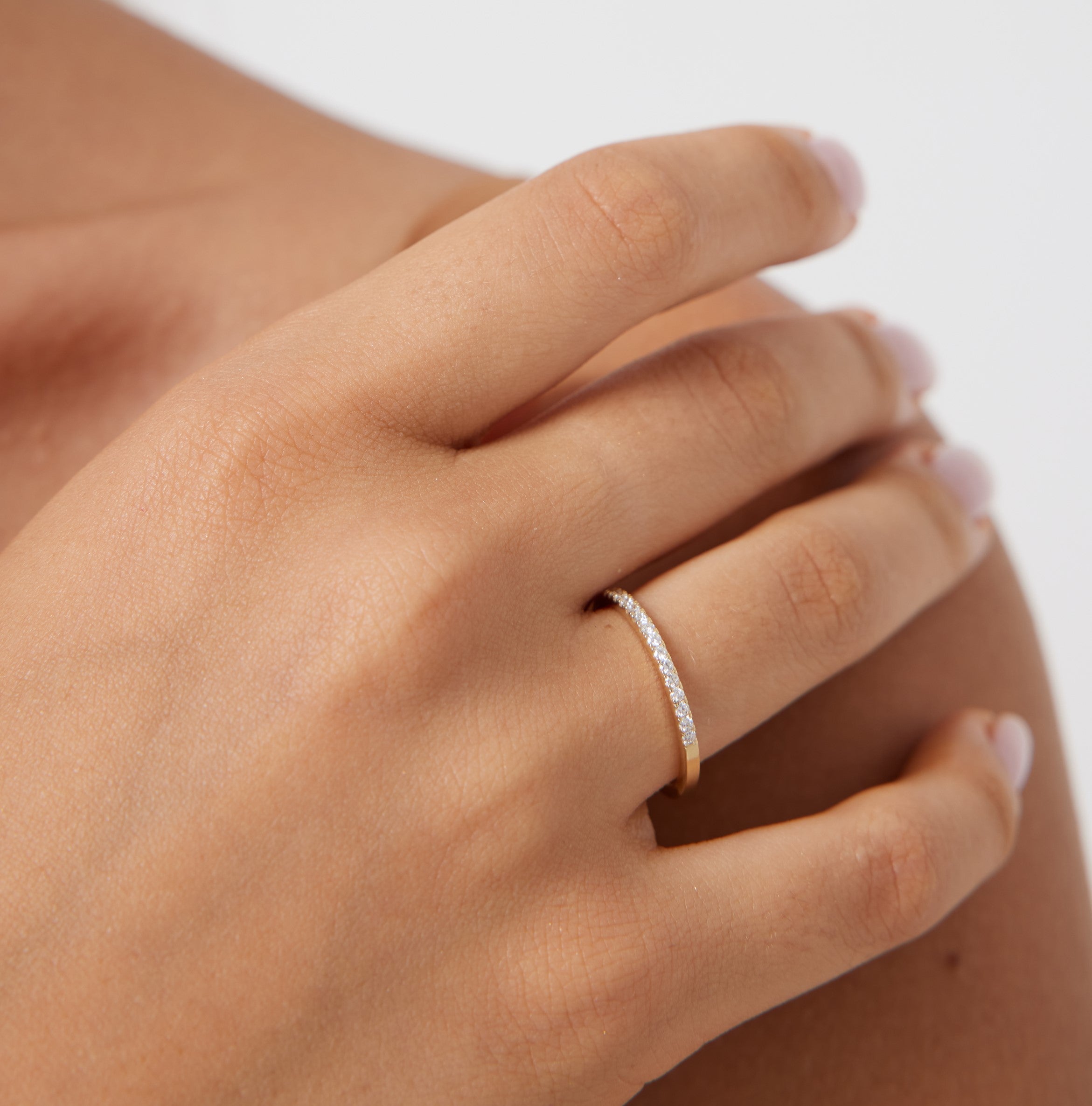 14K yellow gold women's diamond wedding band with 15 round diamonds showcased on a hand.