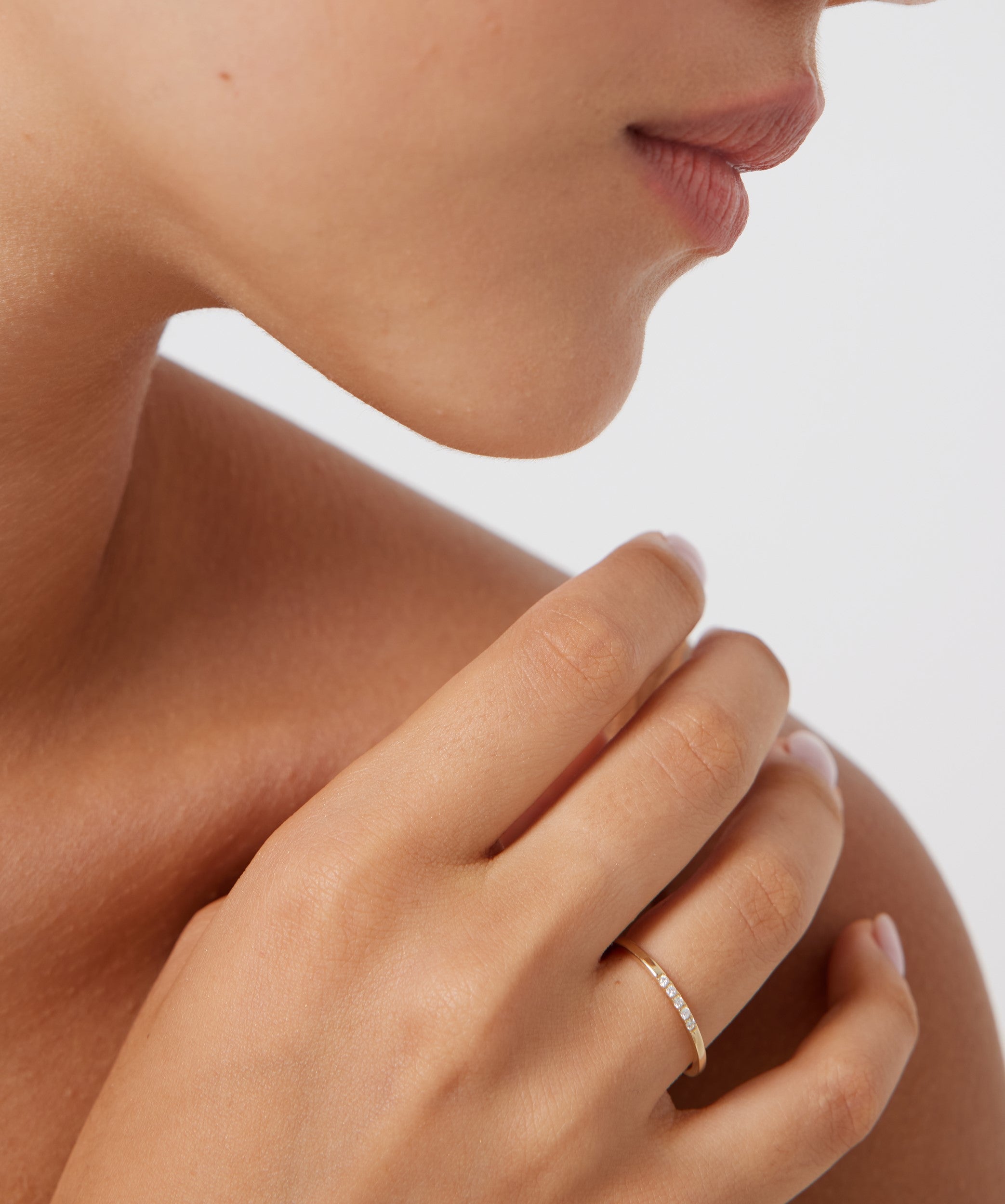 Elegant woman wearing a 14K gold half eternity diamond wedding band on her finger.