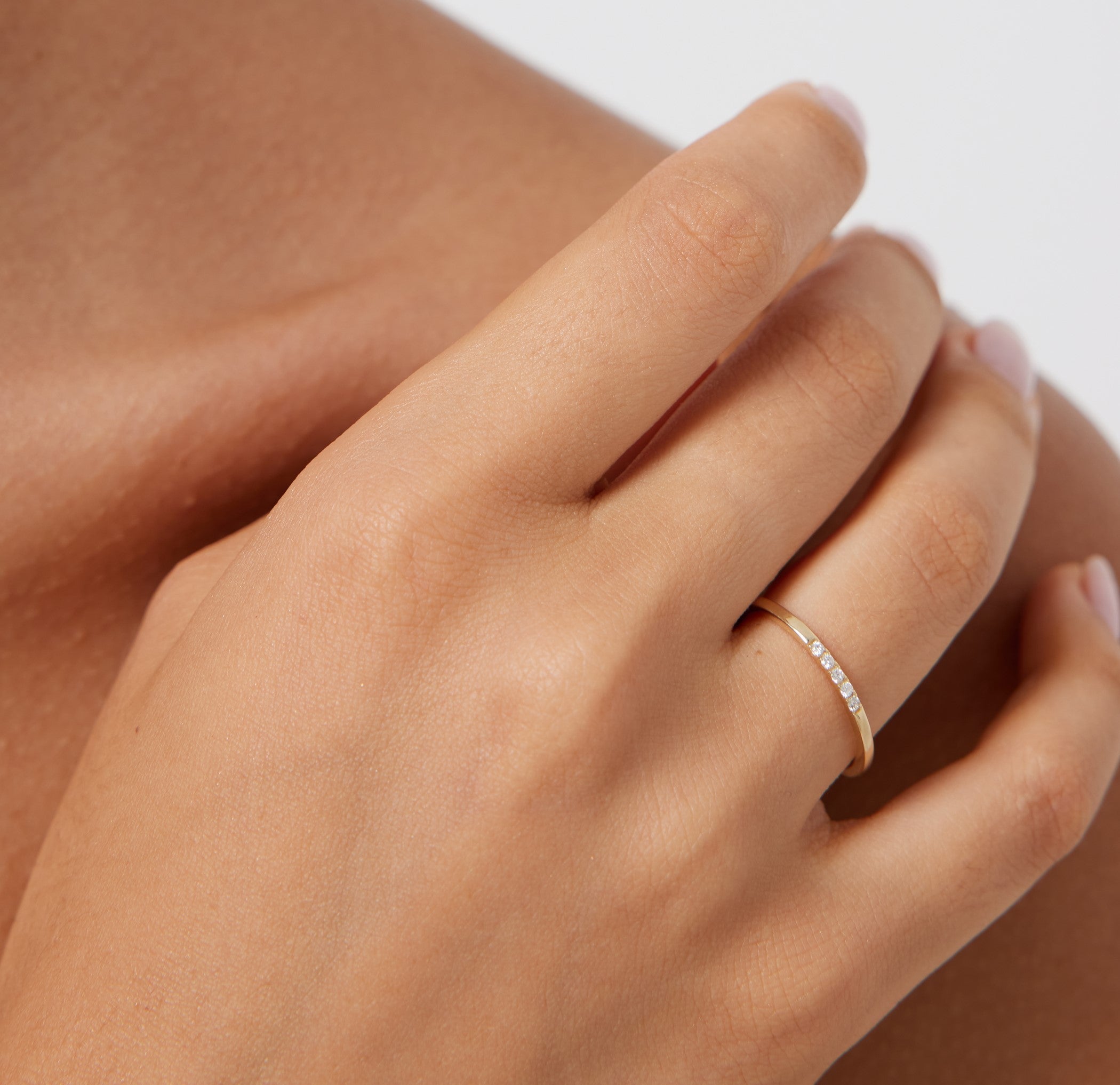 14K gold half eternity diamond wedding band worn on a hand, showcasing minimalist design with five round diamonds.
