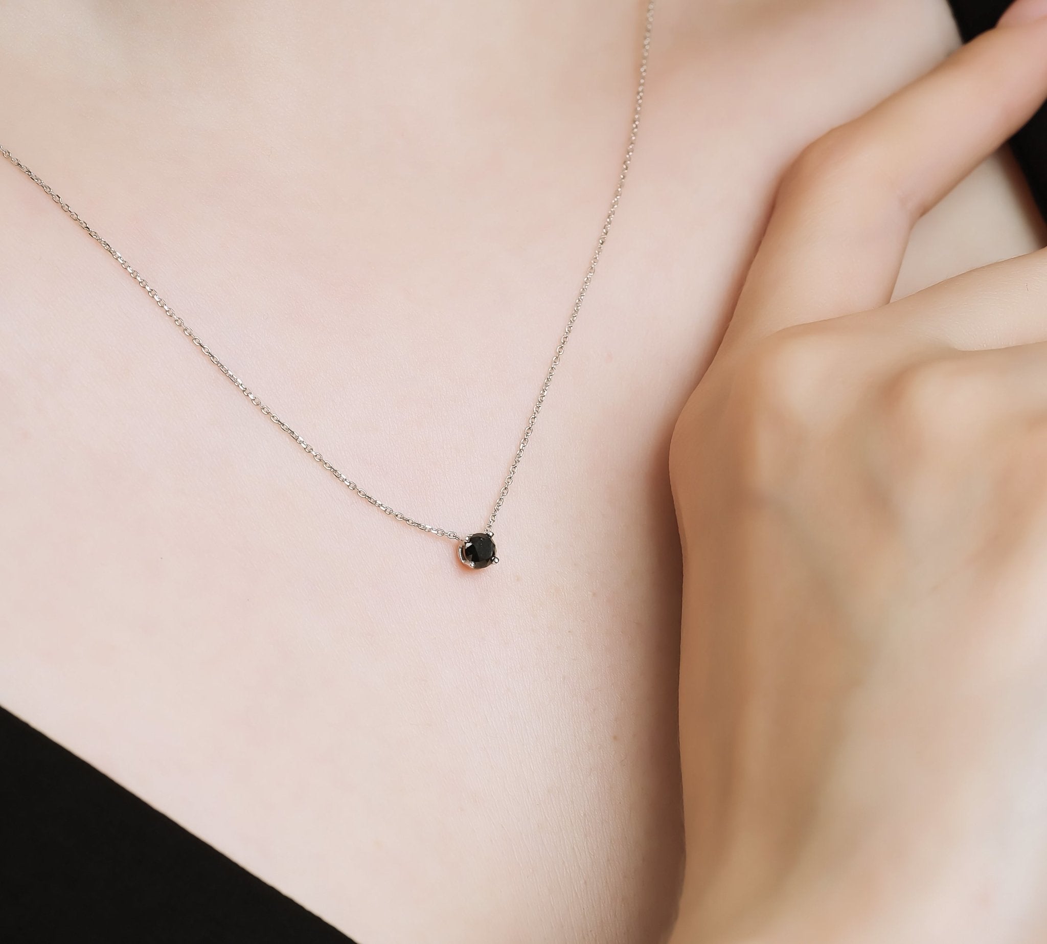Dainty 14K white gold black diamond solitaire necklace worn on a neck, showcasing its minimalist design.