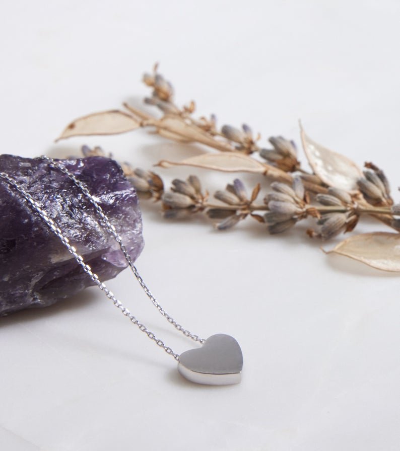 14K white gold dainty heart necklace resting on a crystal with dried flowers in the background, elegant minimalist design.