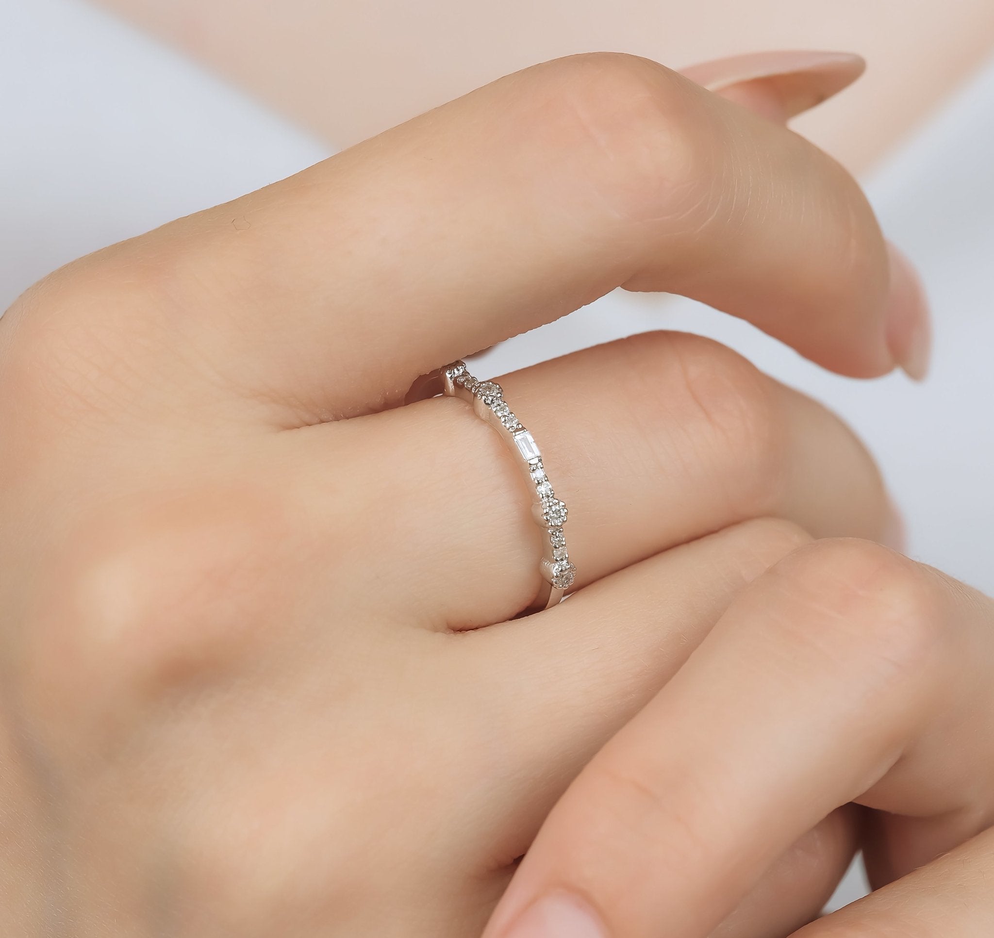14K white gold baguette diamond eternity wedding band worn on a hand, featuring round and baguette diamonds.