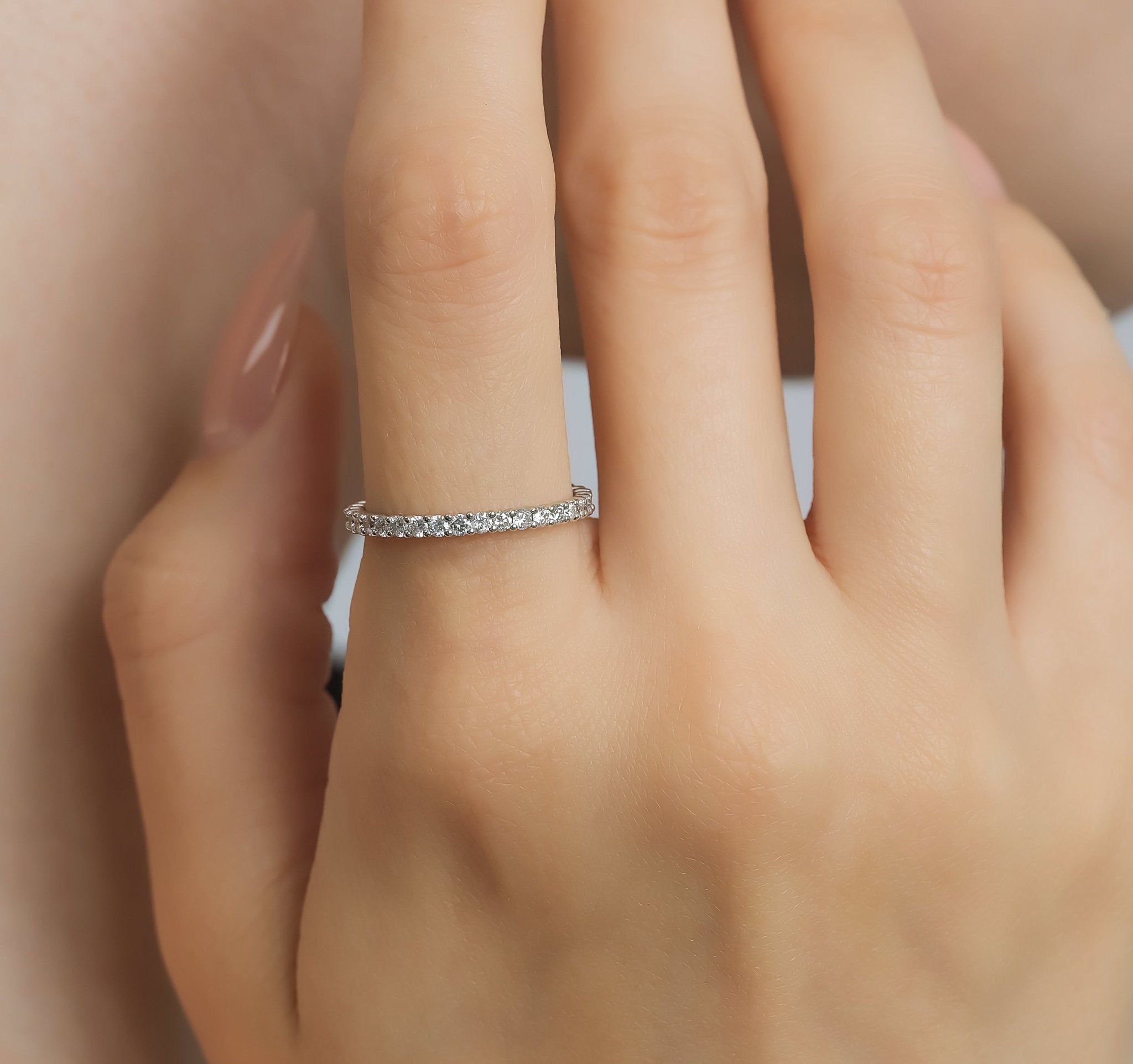 14K gold full eternity diamond wedding ring on a woman's hand, featuring 34 round diamonds and a shiny finish.