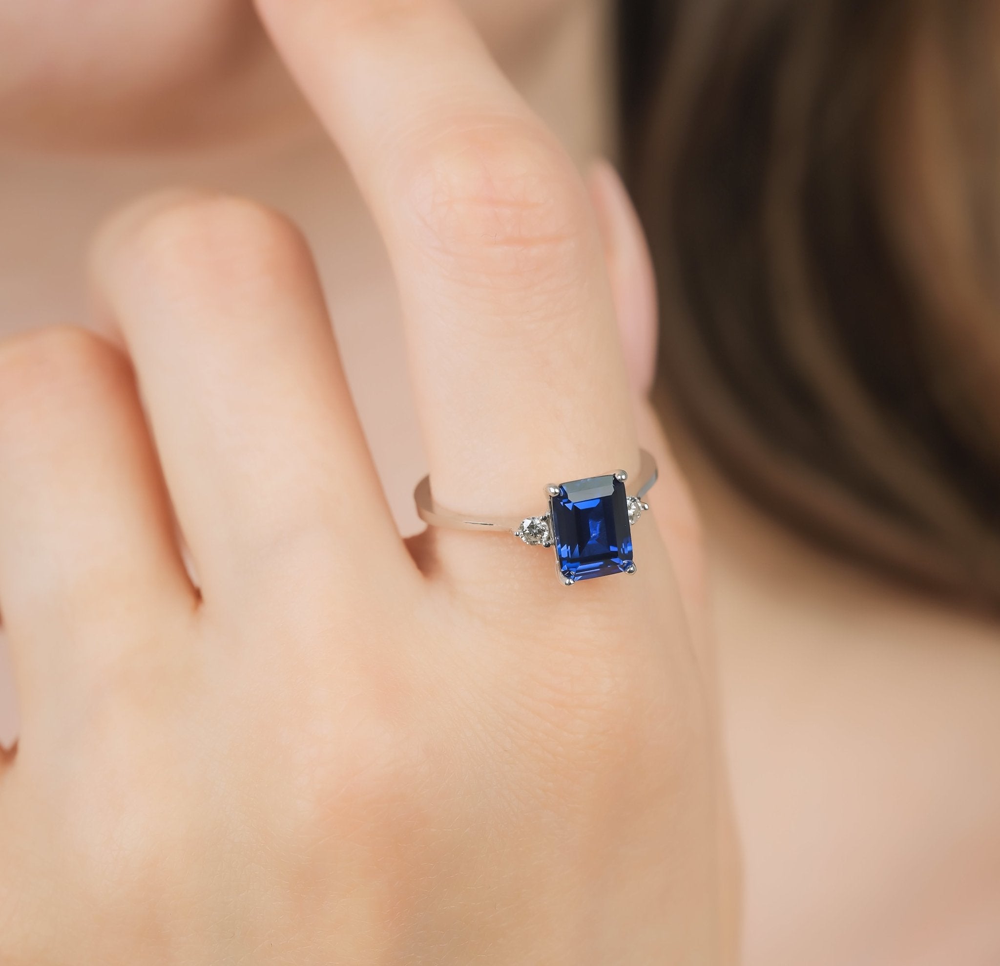 14K white gold emerald cut sapphire and diamond ring being worn, featuring a 1.75 carat sapphire and accent diamonds.