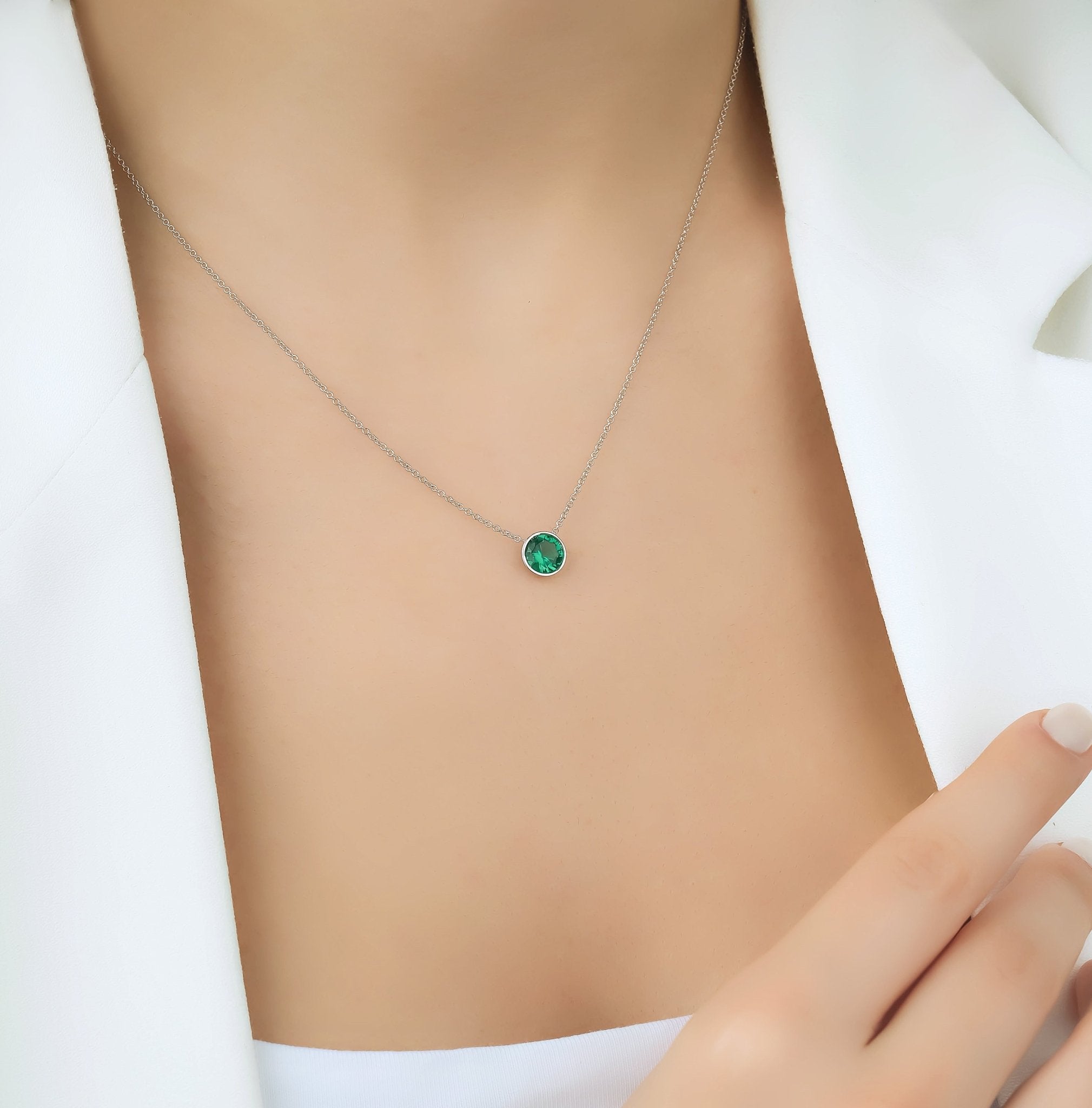 14K white gold 6mm bezel set solitaire emerald necklace worn on a model's neck, showcasing its minimalist design.