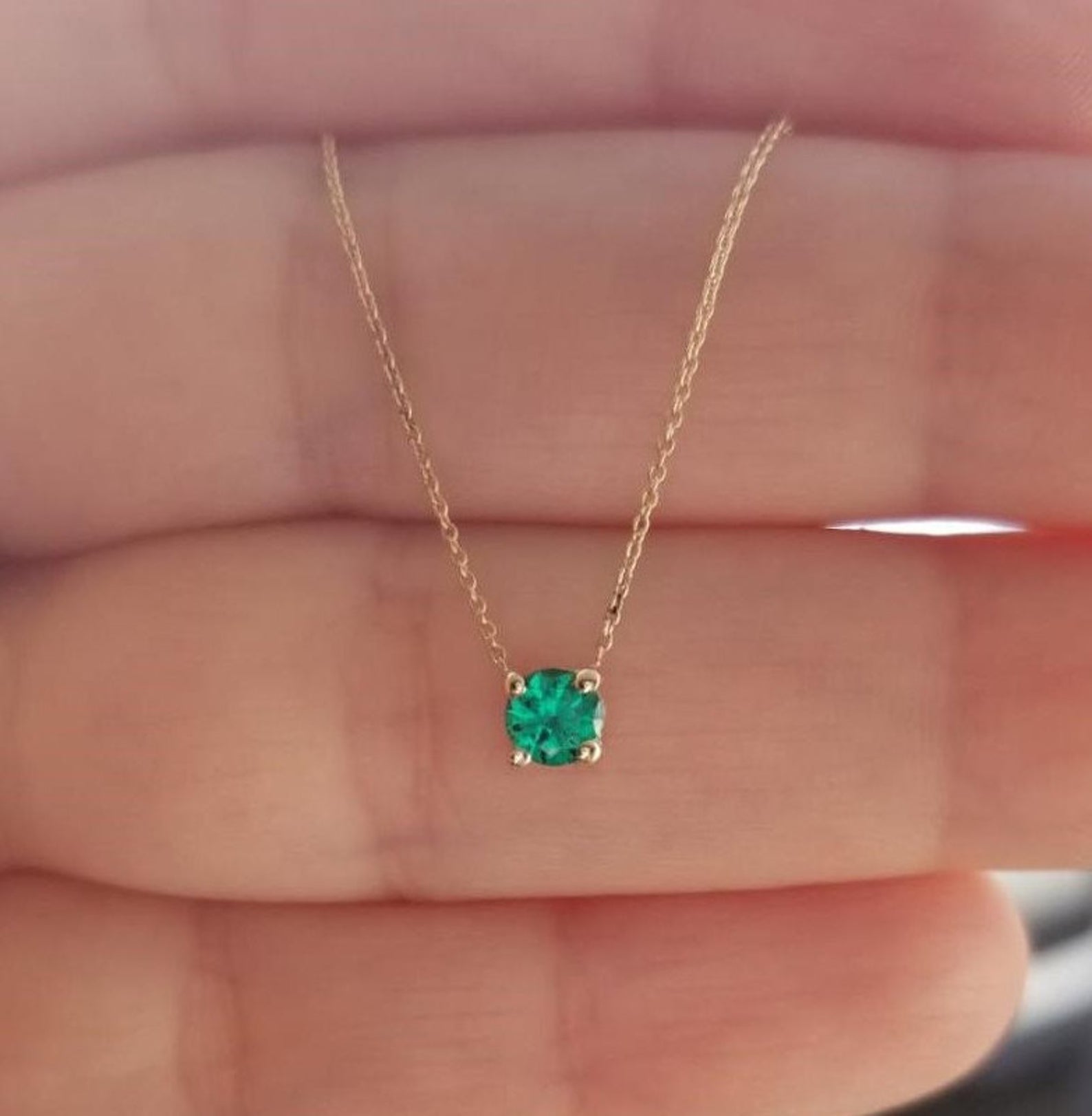 14K white gold minimalist solitaire emerald necklace in a prong setting shown in hand, perfect for May birthstone.