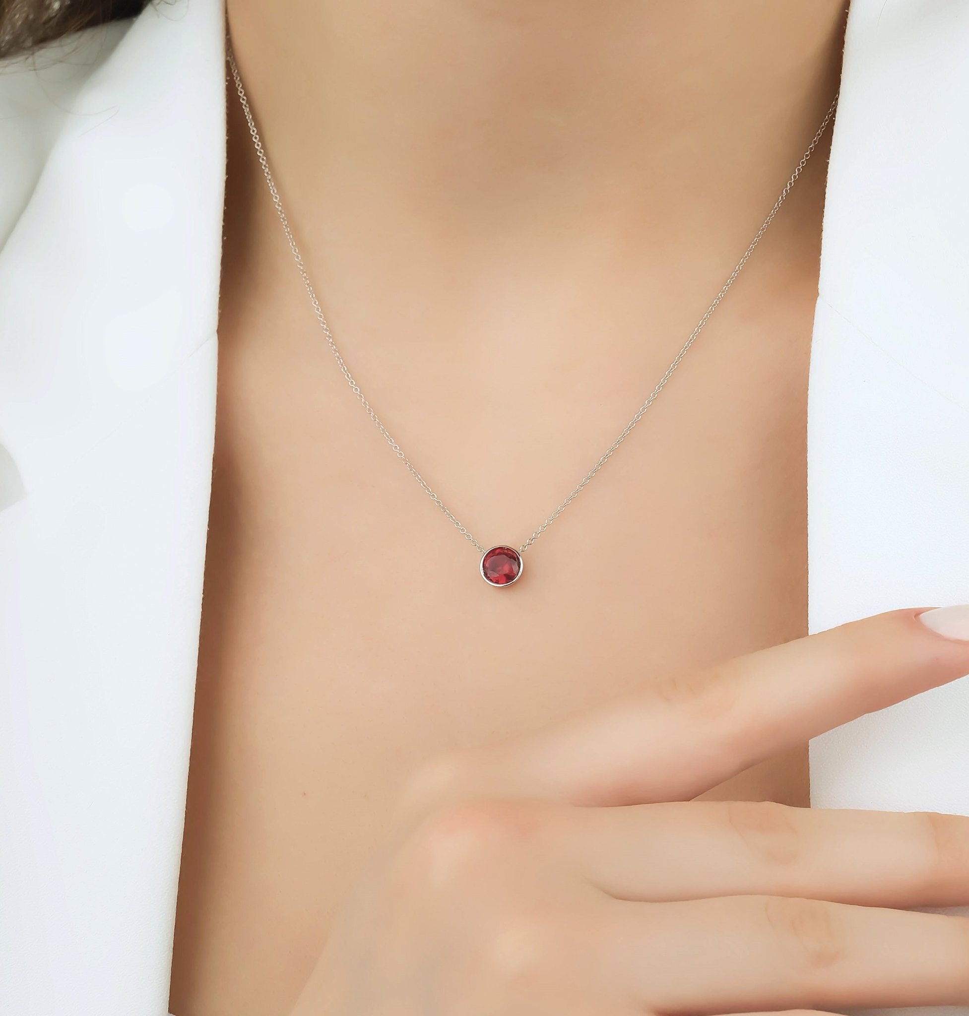 14K white gold bezel set 6mm solitaire ruby necklace worn on a person's neck, featuring a minimalist design.